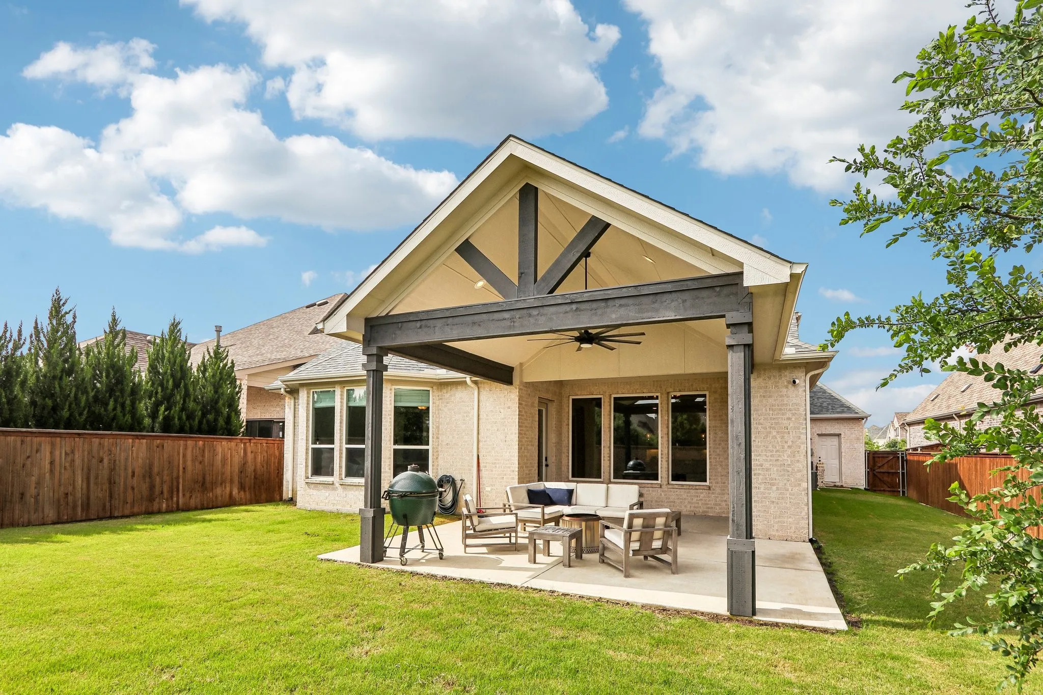 Expansive backyard with a covered patio, vaulted ceiling, and ceiling fan