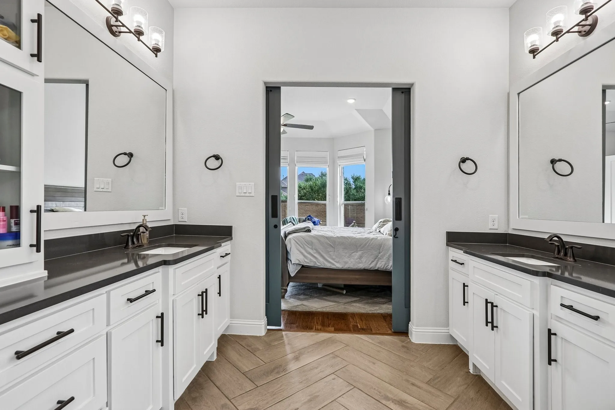 Dual vanities with dark countertops, white cabinetry, and matte black hardware