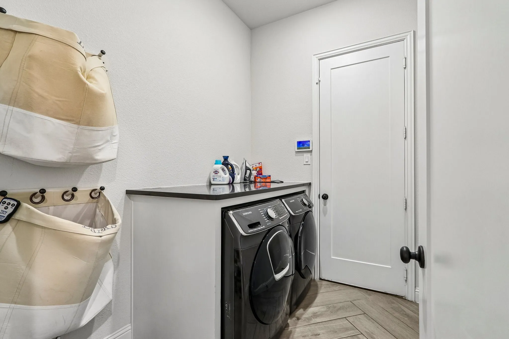 Laundry area featuring a built-in counter, dark flat-panel cabinetry, and herringbone-patterned wood-finish flooring