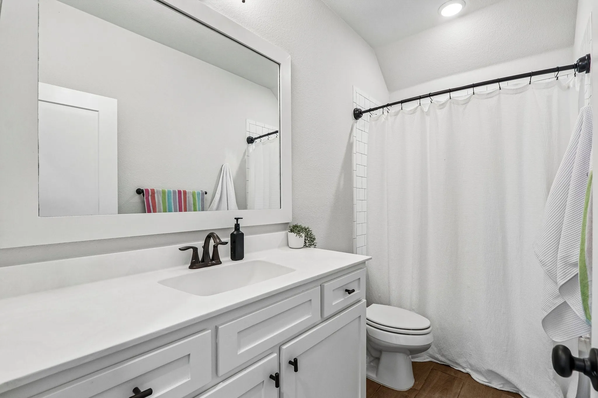 Single vanity with white countertop, integrated sink, and bronze-finish faucet