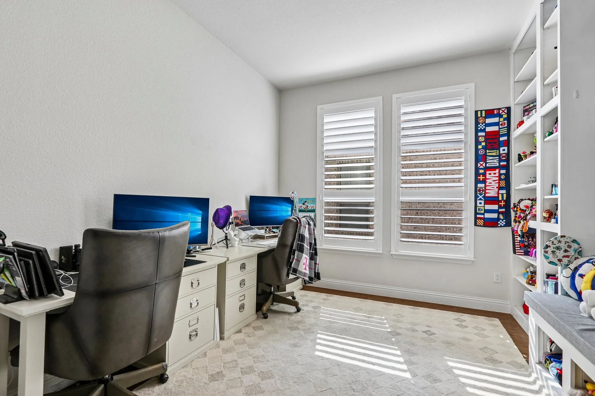 Recessed wall shelving, two windows with louvered shutters, and wood-finish flooring