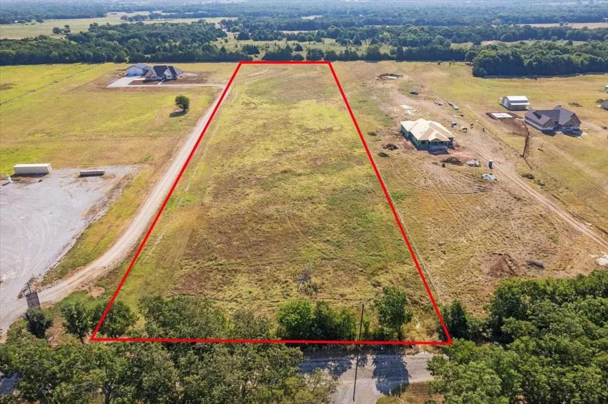 Expansive undeveloped land featuring a clear perimeter, mature trees along the southern boundary, and surrounding open fields