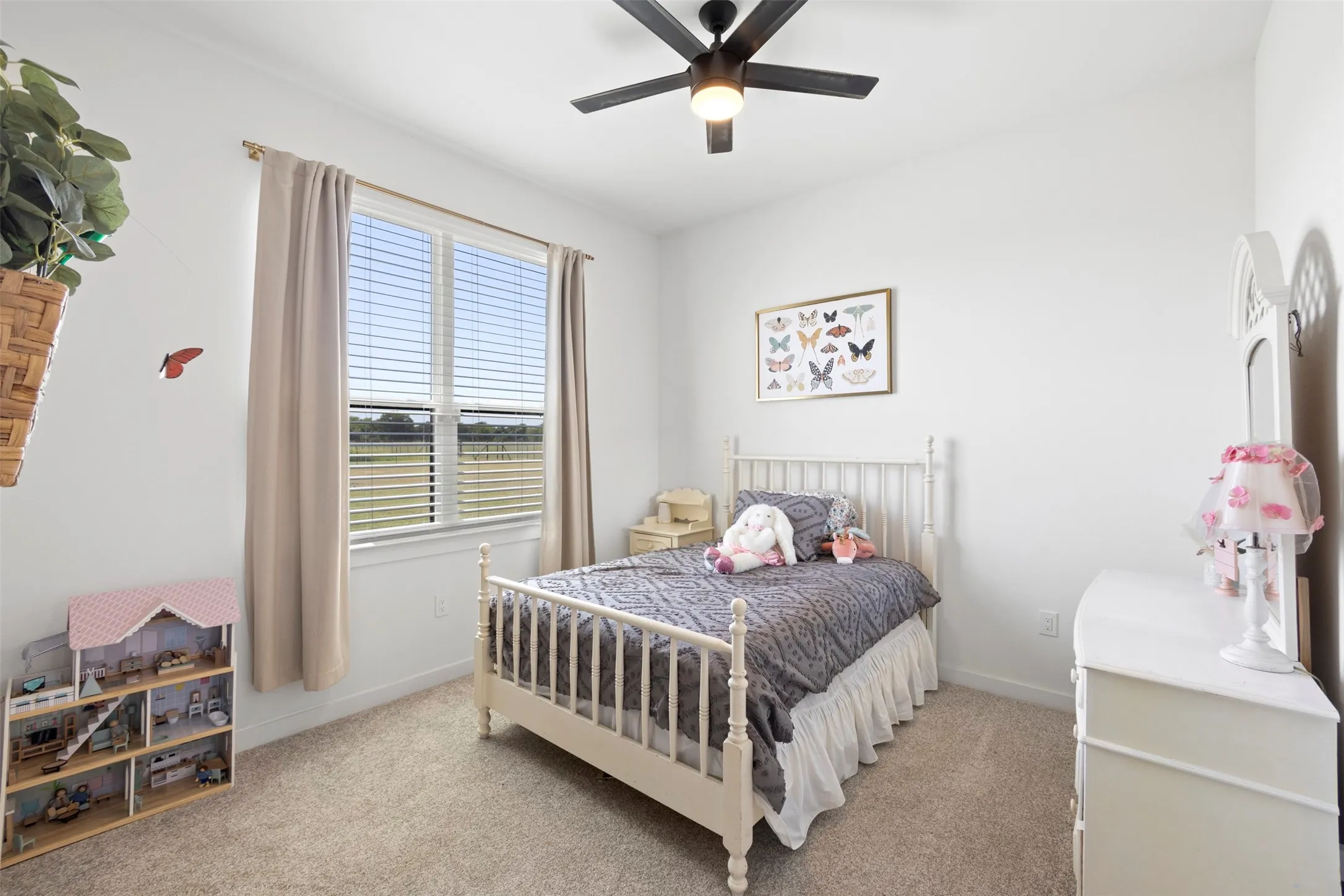 Plush carpet flooring, neutral wall tones, a ceiling fan with integrated lighting, and a large window with horizontal blinds