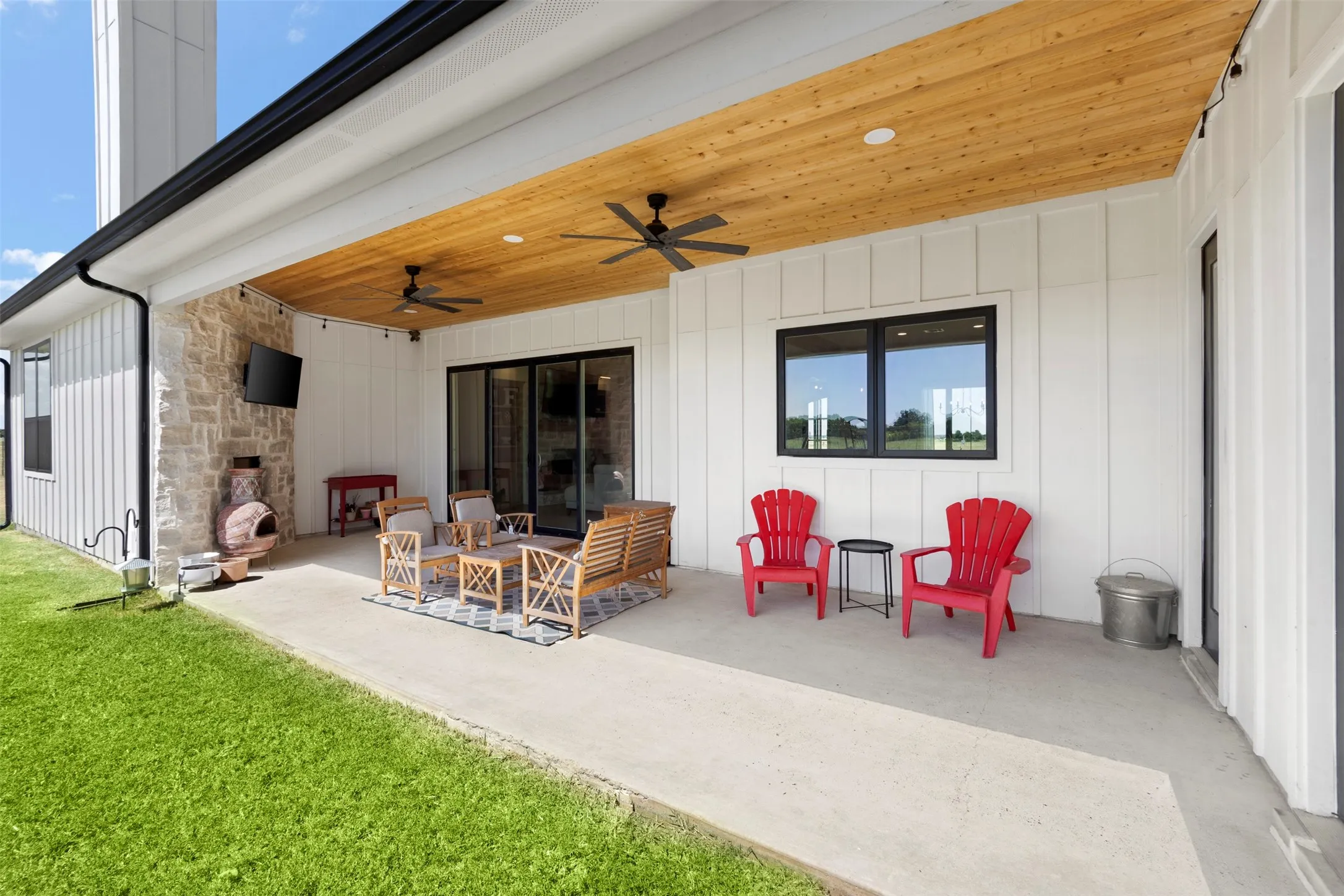 Expansive covered patio with a wood-plank ceiling, recessed lighting, and ceiling fans