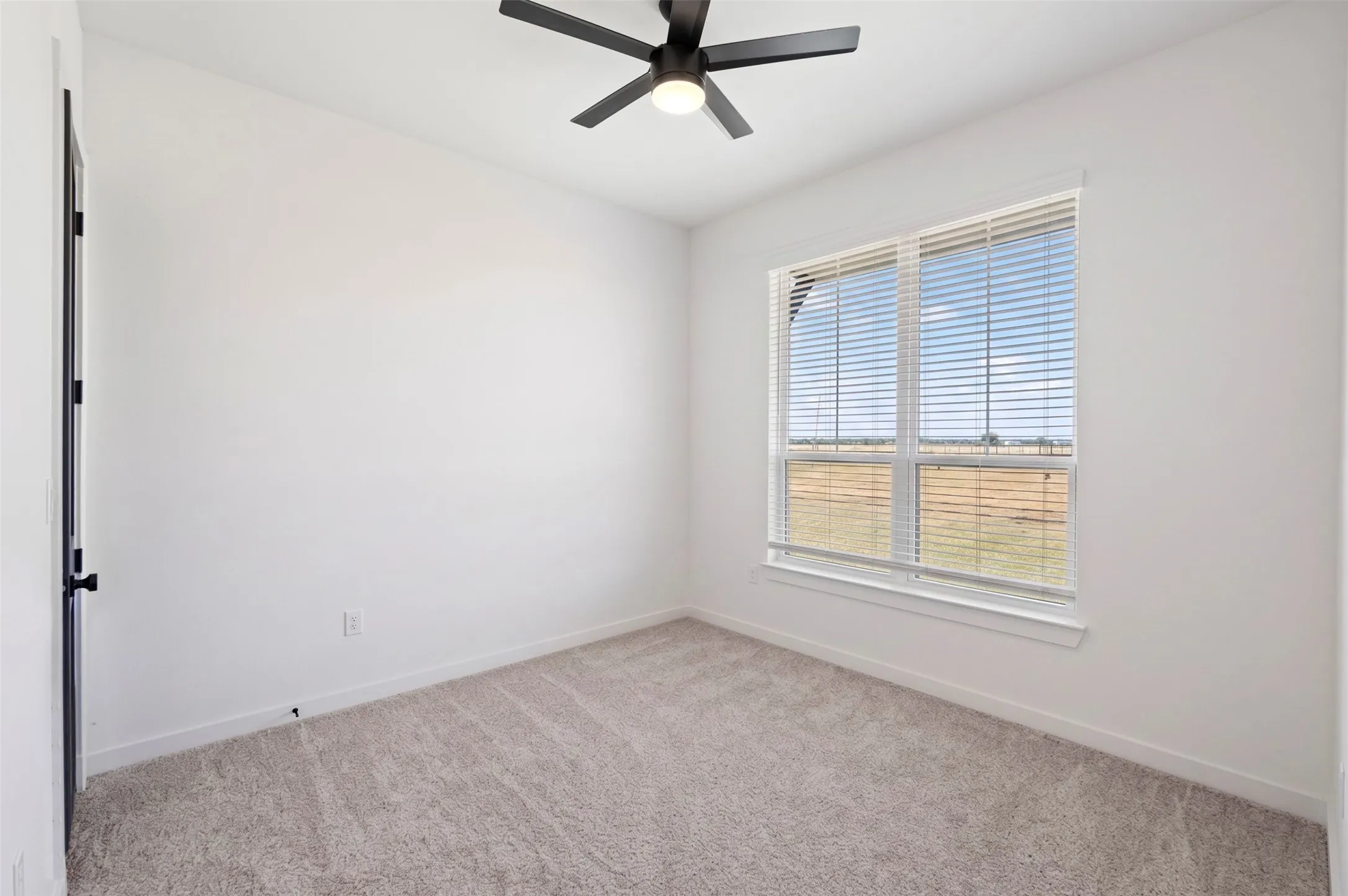 Neutral wall color, carpeted flooring, window with horizontal blinds, and a ceiling fan with integrated lighting