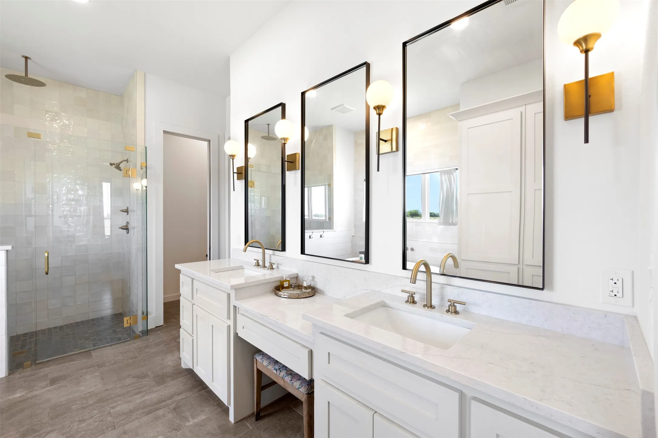 Dual vanity with white cabinetry, light-toned countertops, and gold-finish fixtures