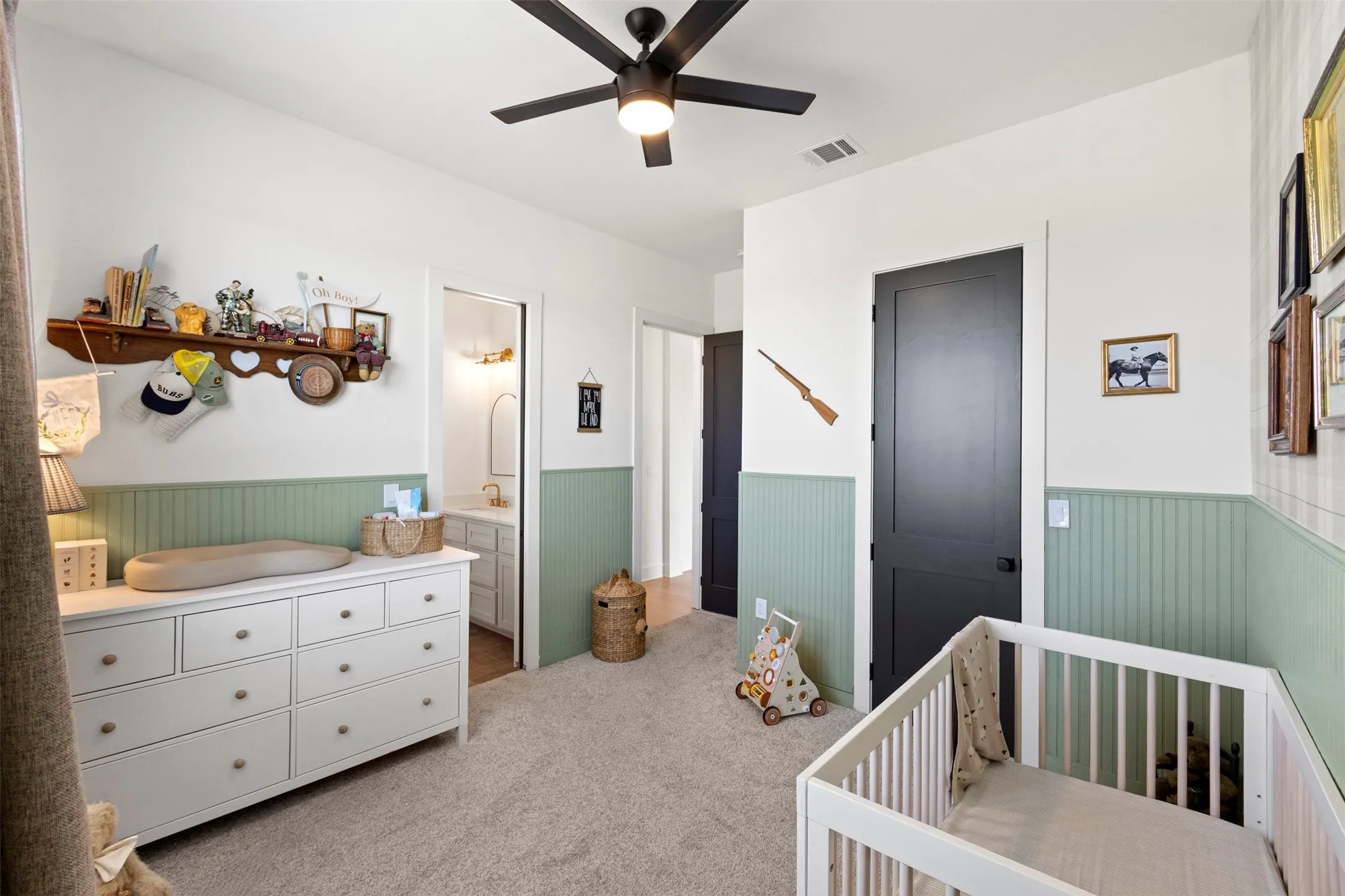 Light-toned wall paneling with an upper wall section, dark-toned interior doors, and a ceiling fan with integrated lighting
