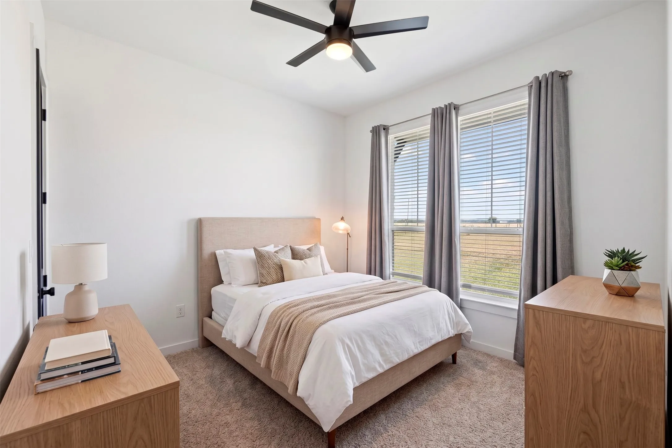 Carpeted room with a ceiling fan, two windows with blinds, and white walls
