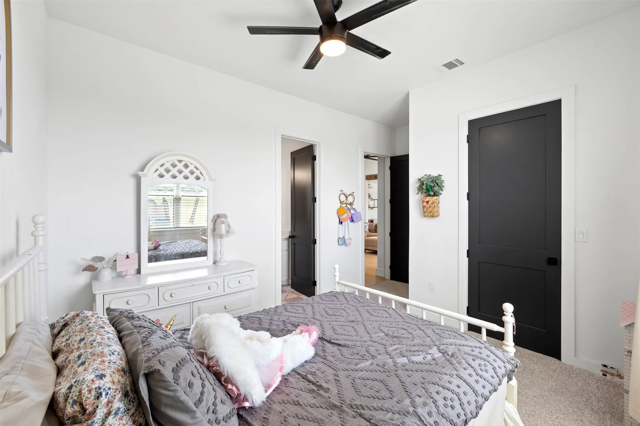 White walls with black paneled doors, ceiling fan with integrated lighting, and carpeted flooring
