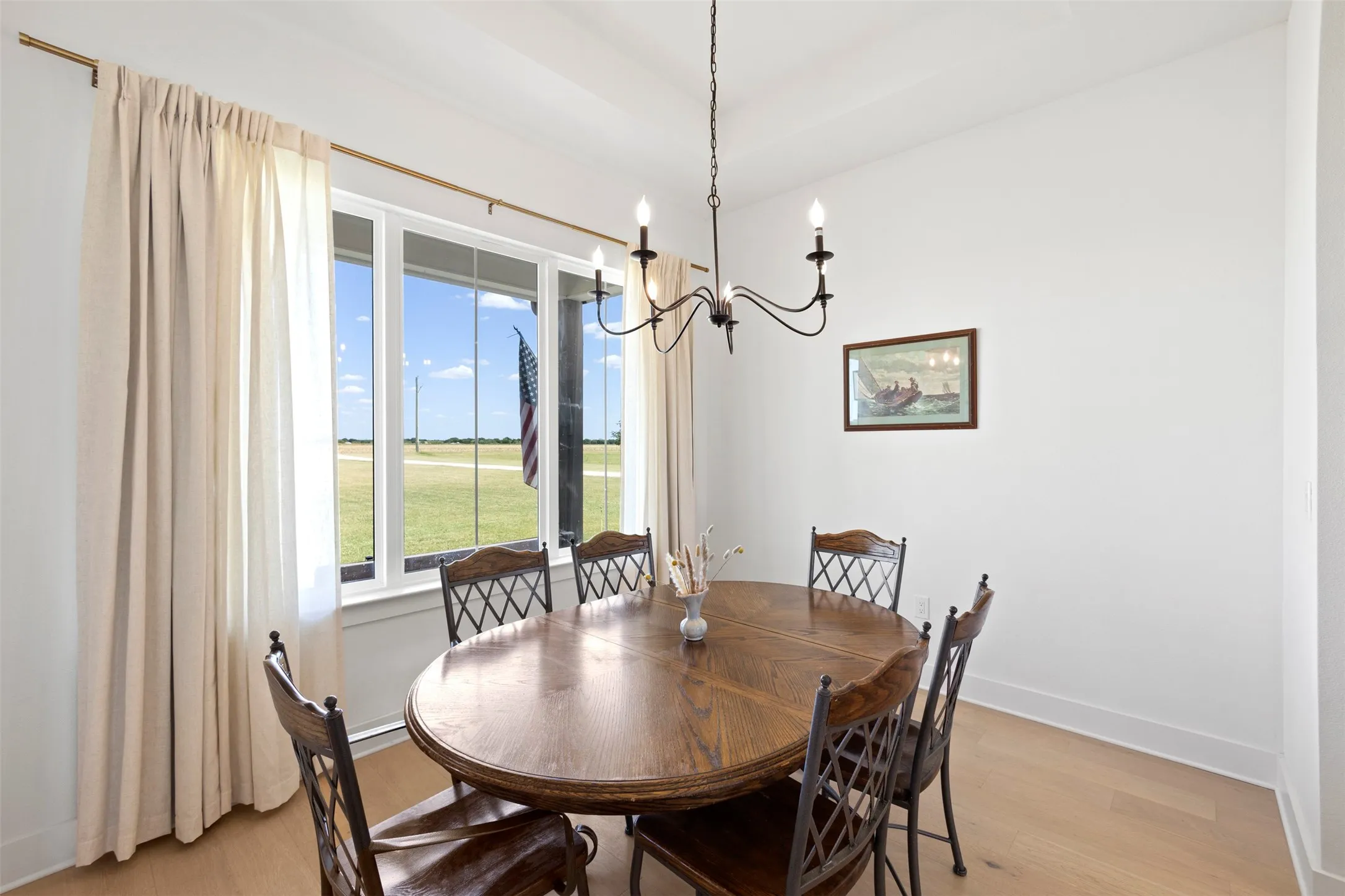 Tray ceiling with a chandelier, wood-finish flooring, and expansive windows