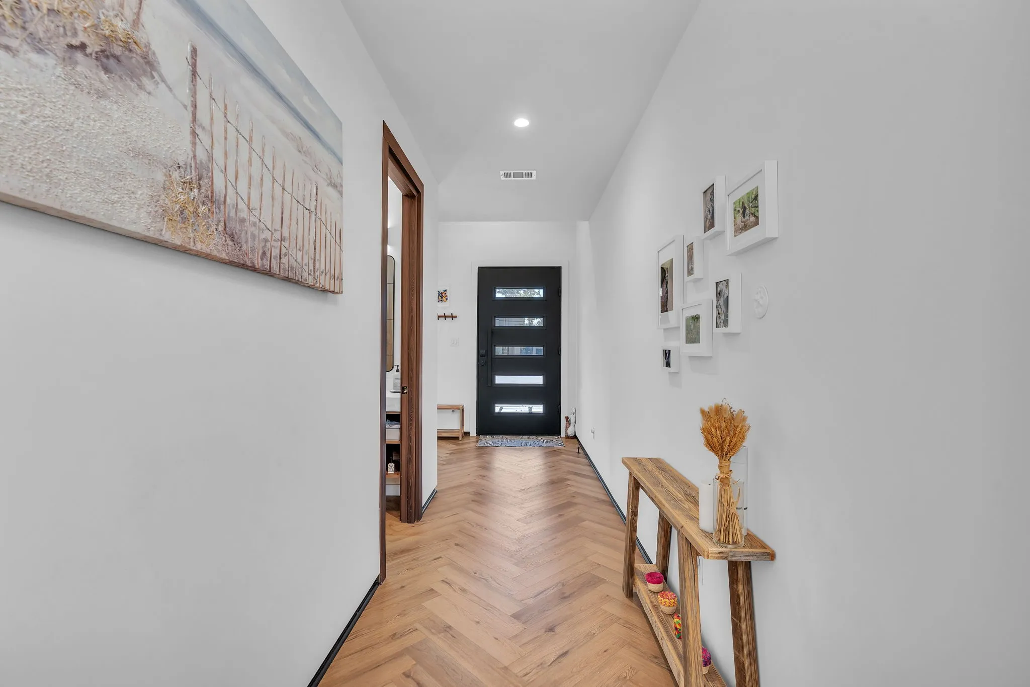 Herringbone wood-finish flooring, white walls, and wood-trim doorways