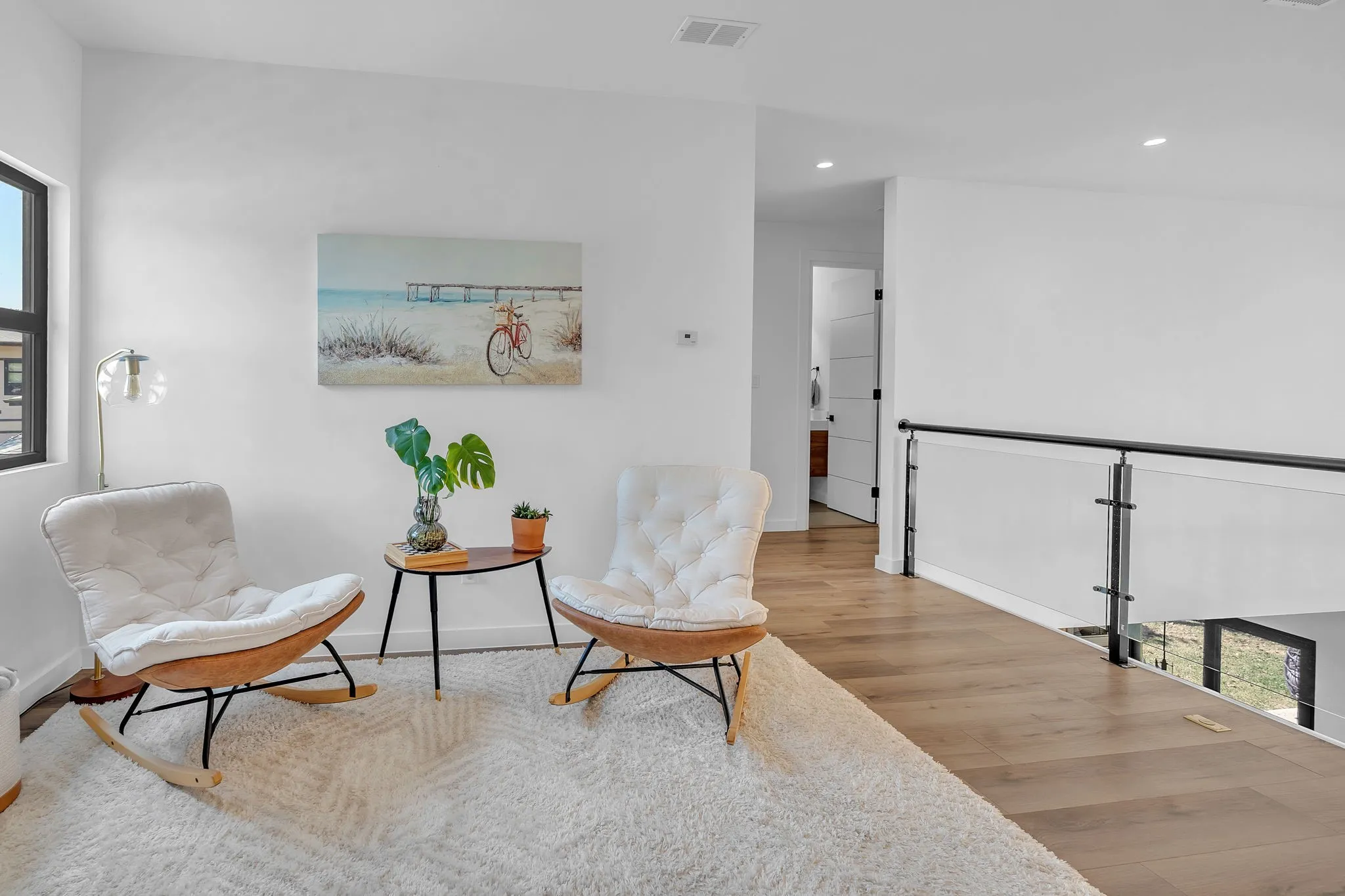 Wood-finish flooring, recessed lighting, and a contemporary glass and metal railing system