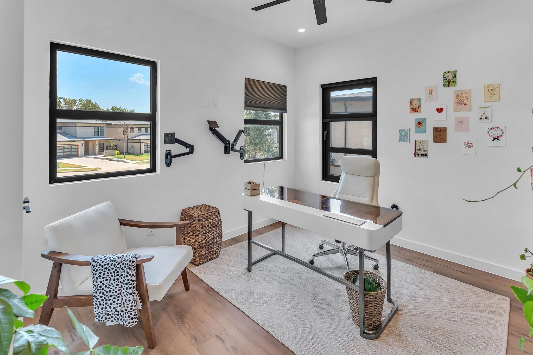 Bright interior featuring multiple windows with dark frames, wood-finish flooring, and a ceiling fan