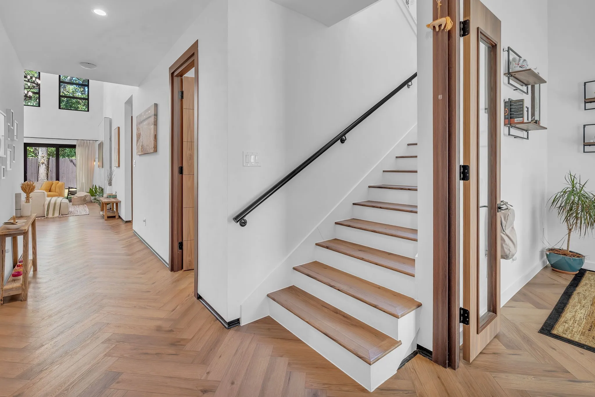 Herringbone wood-finish flooring, white walls, and wood-trim doorways