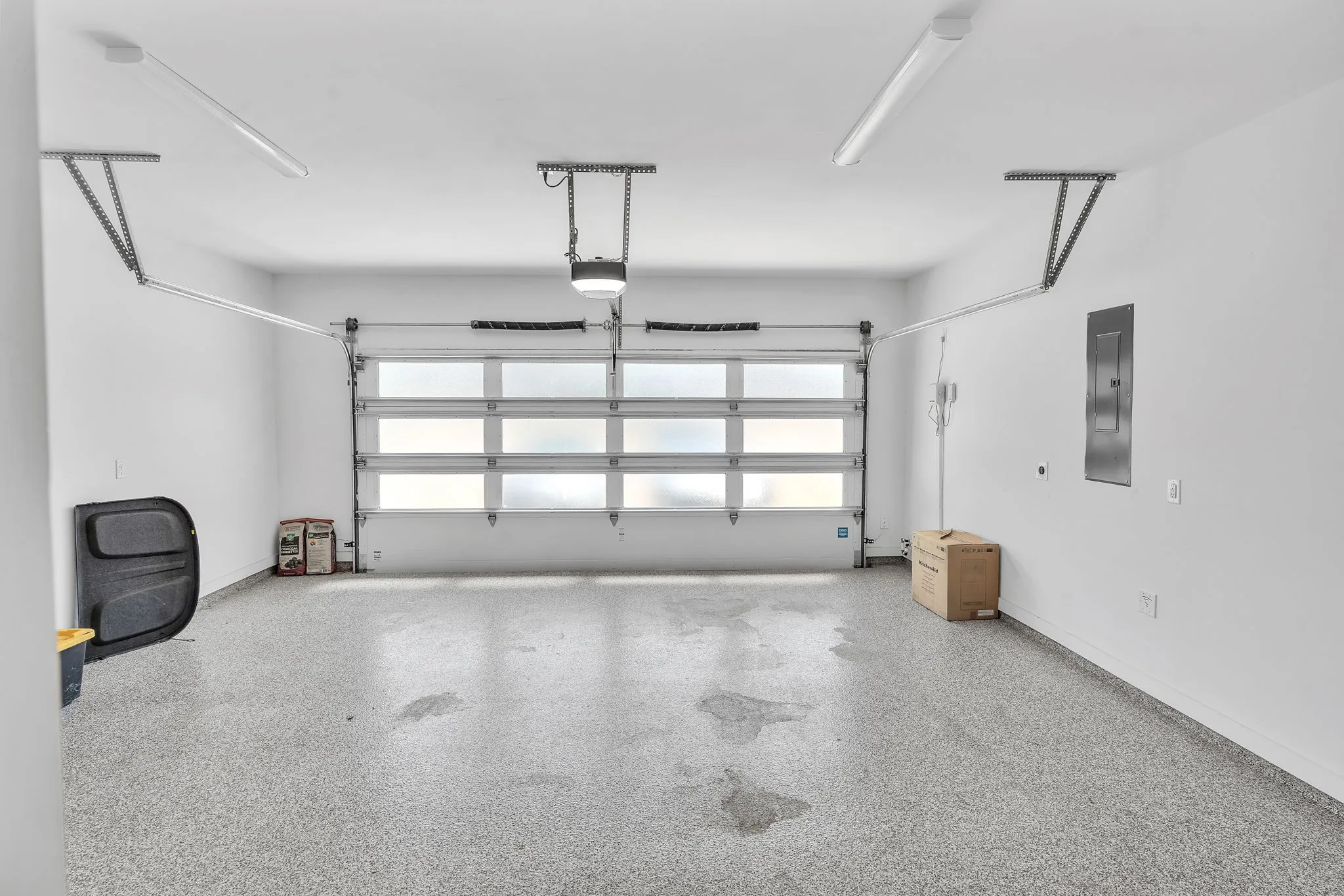 Garage with speckled epoxy flooring, white walls, and a multi-panel frosted glass garage door