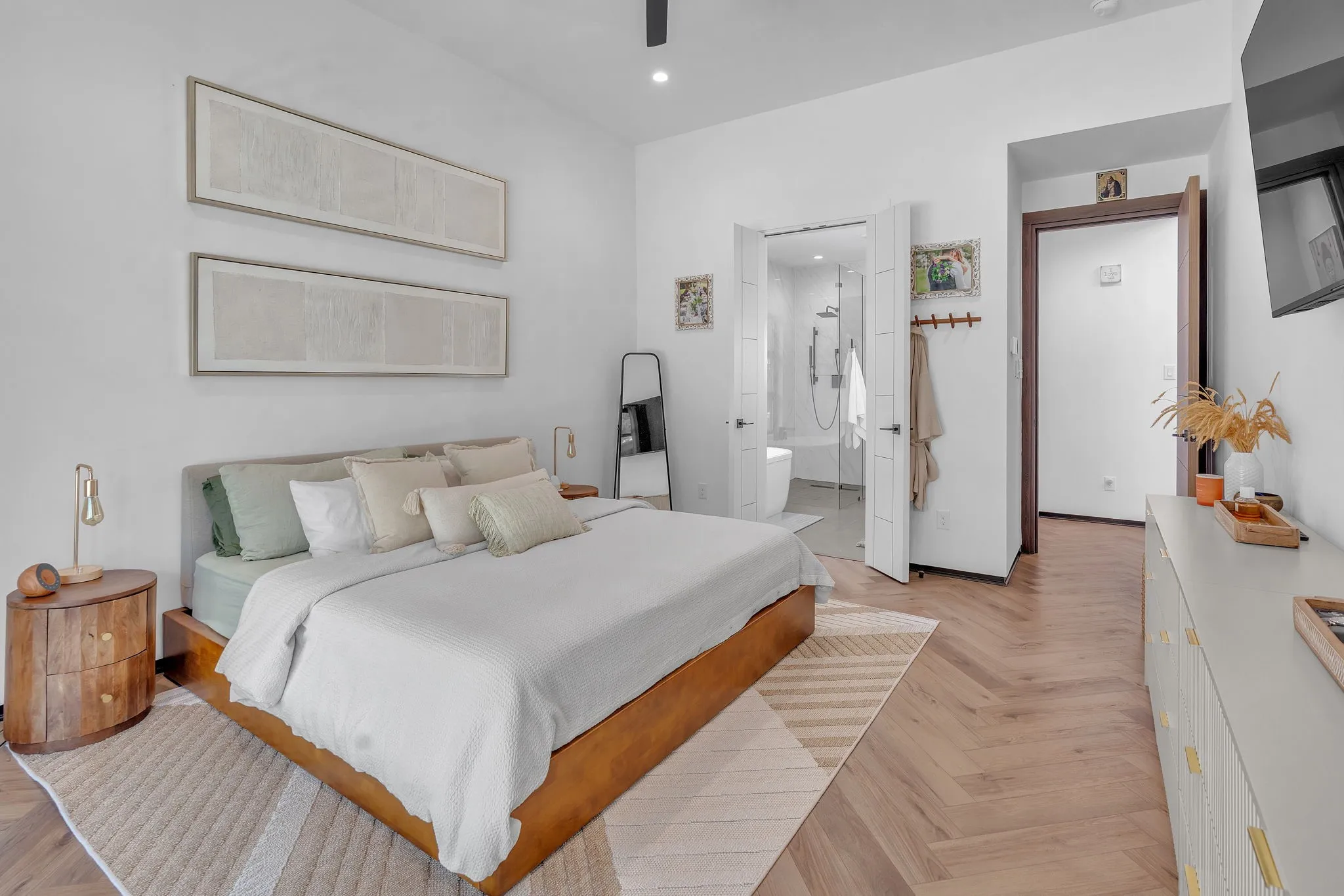 Herringbone wood-finish flooring, white walls, built-in ceiling fan, and double doors opening to a bathroom