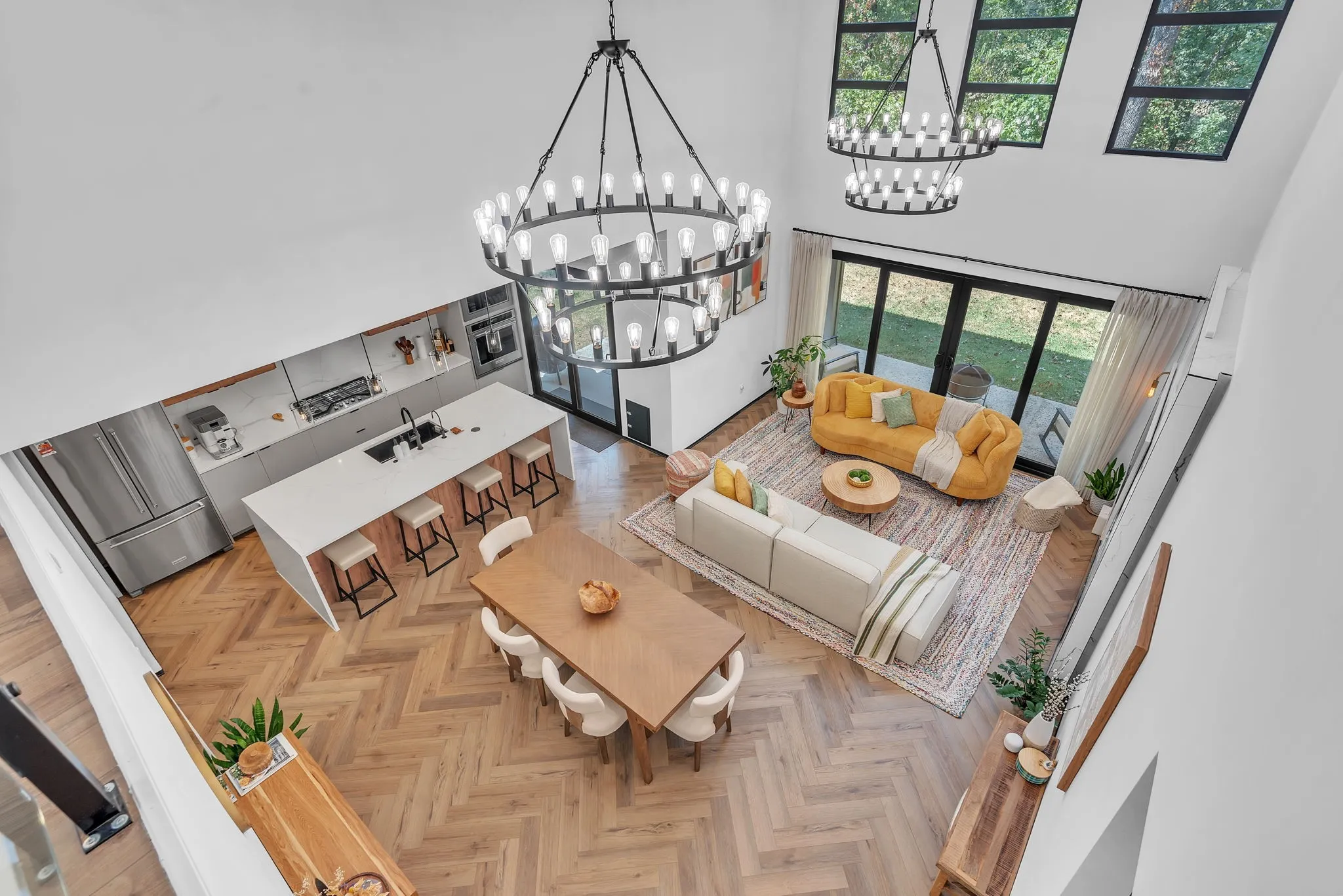 Spacious living area with high ceilings, recessed lighting, and herringbone wood-finish flooring