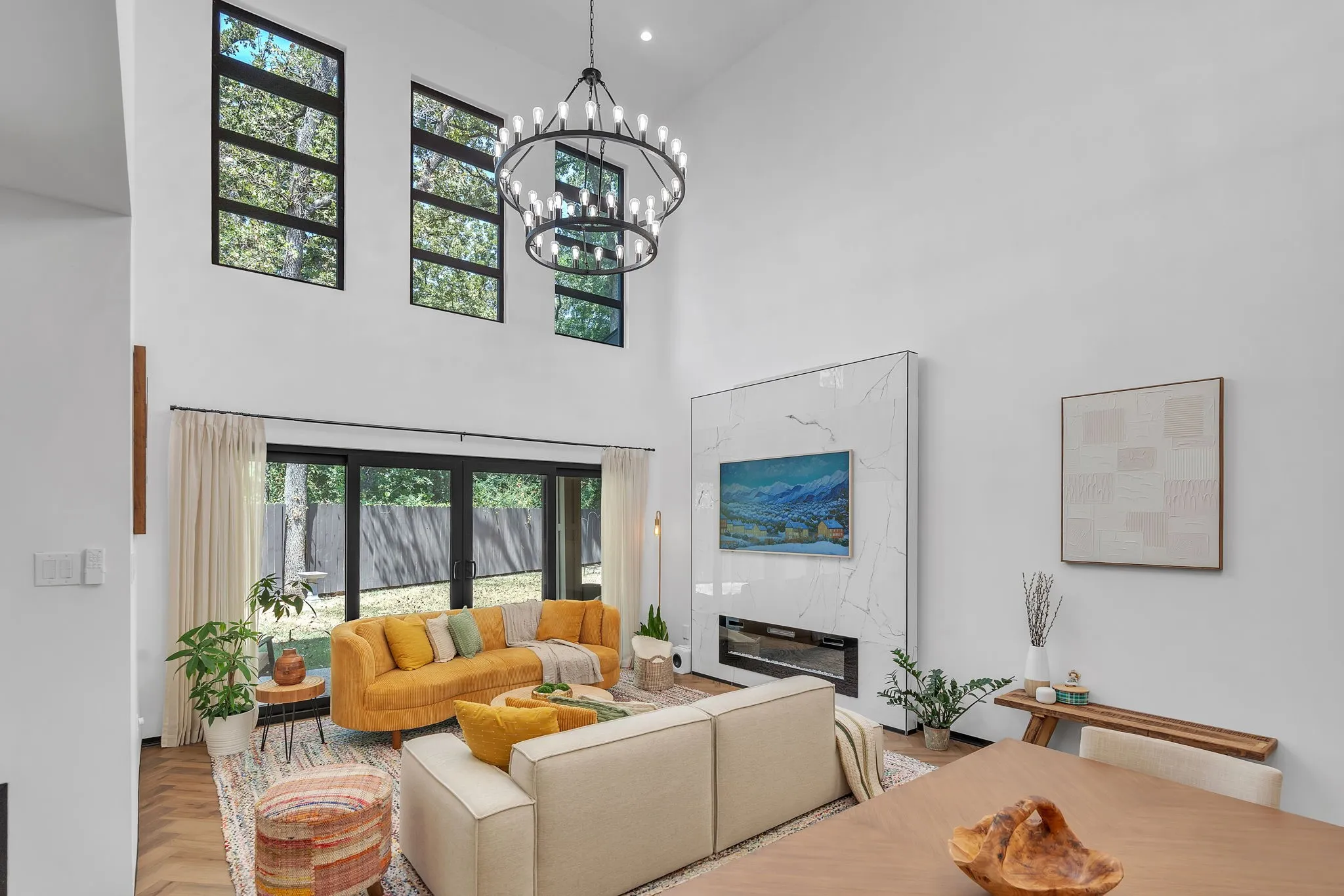 Vaulted ceiling with a multi-tiered chandelier, a fireplace with a stone-finish surround, and wood-finish flooring