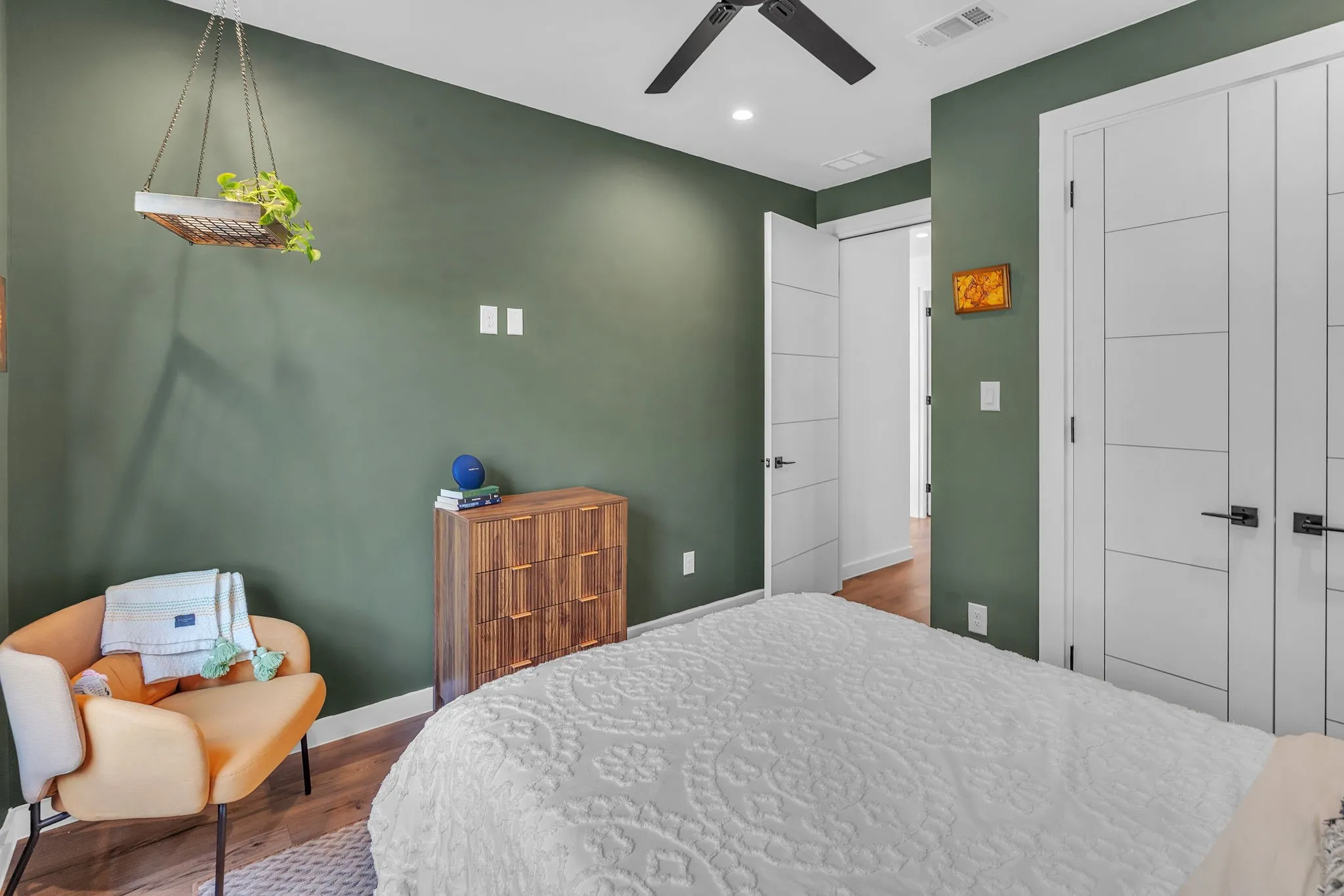 Wood-finish flooring, modern flat-panel interior doors with black hardware, and a ceiling fan