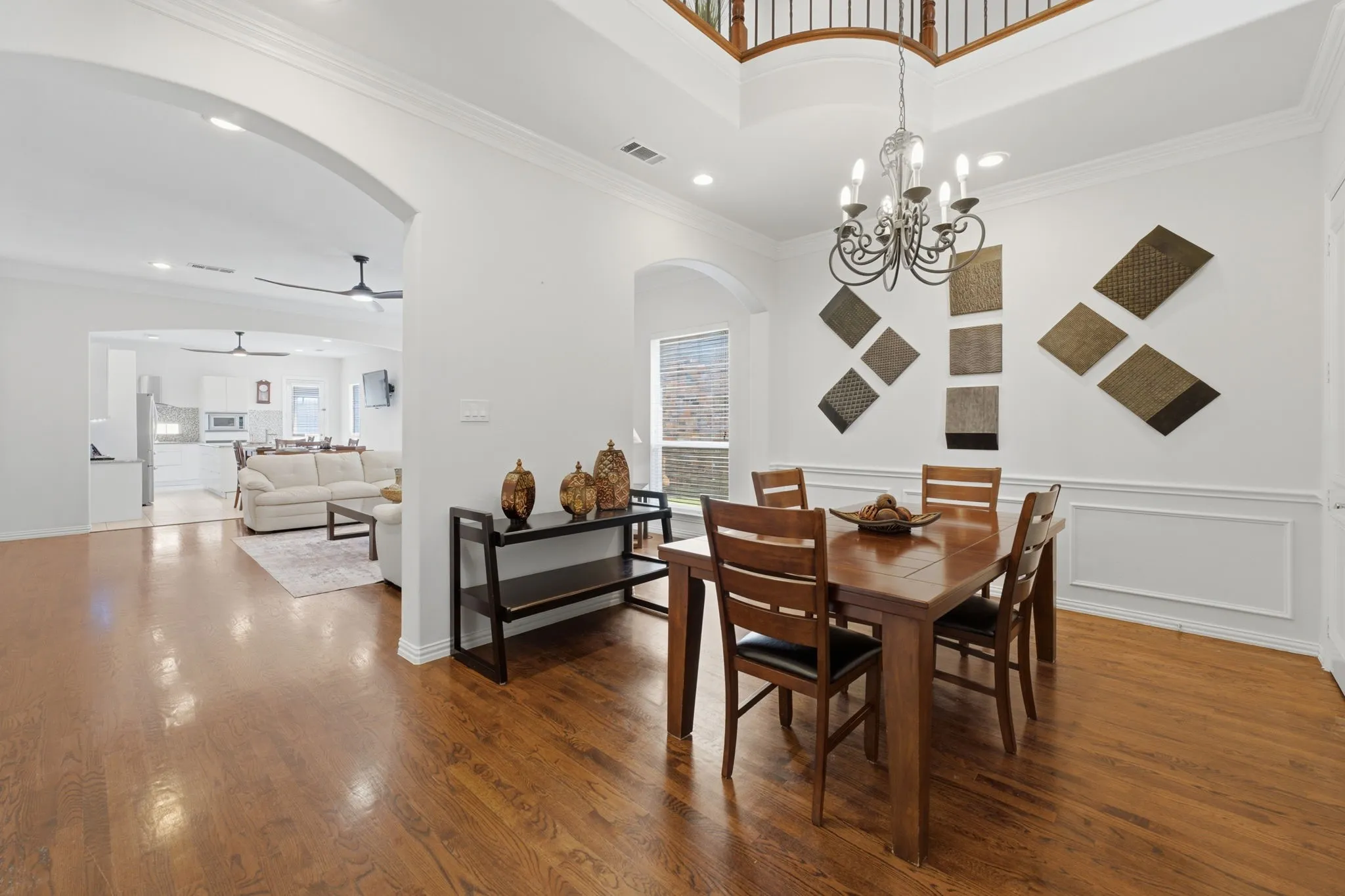 Hardwood flooring, arched doorway, recessed lighting, chandelier lighting, and a two-story ceiling