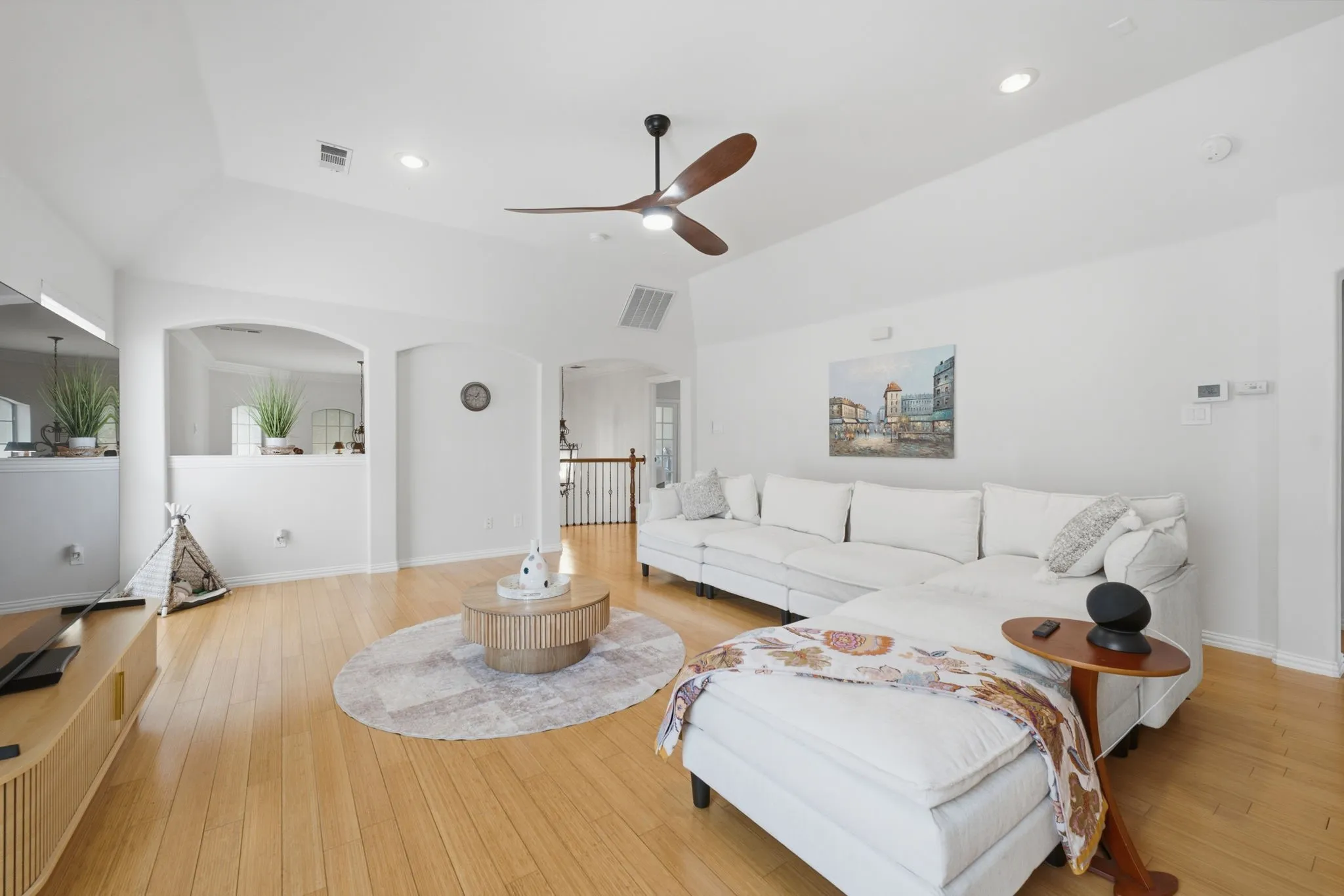 Vaulted ceiling, recessed lighting, wood-finish flooring, half-wall partition, and archway