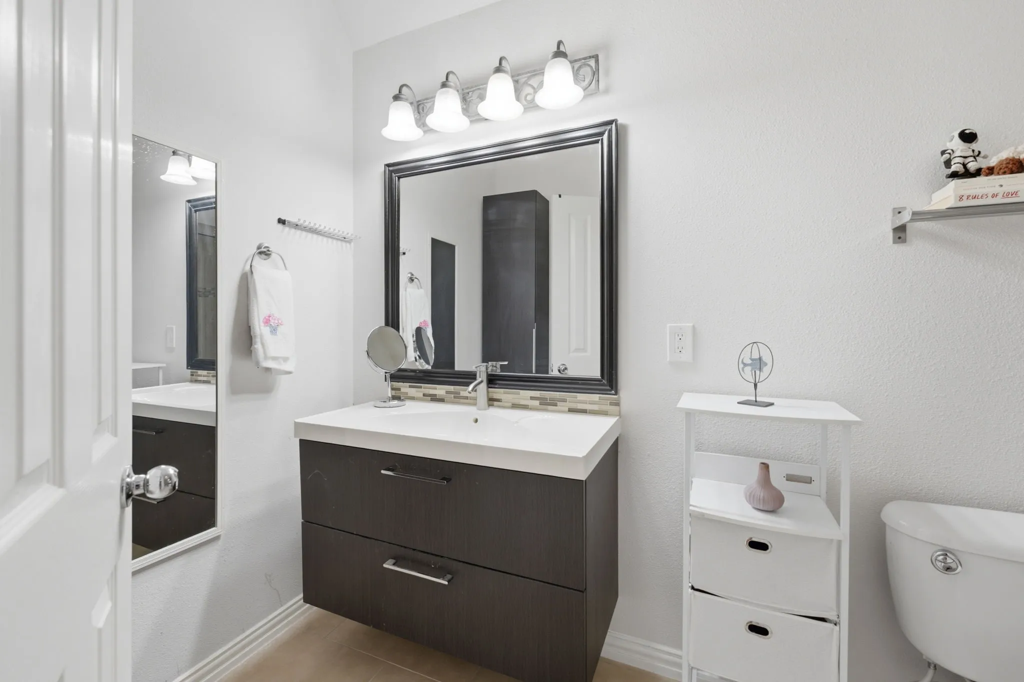 Floating wood-finish vanity with an integrated sink, framed mirror, and a decorative tile backsplash