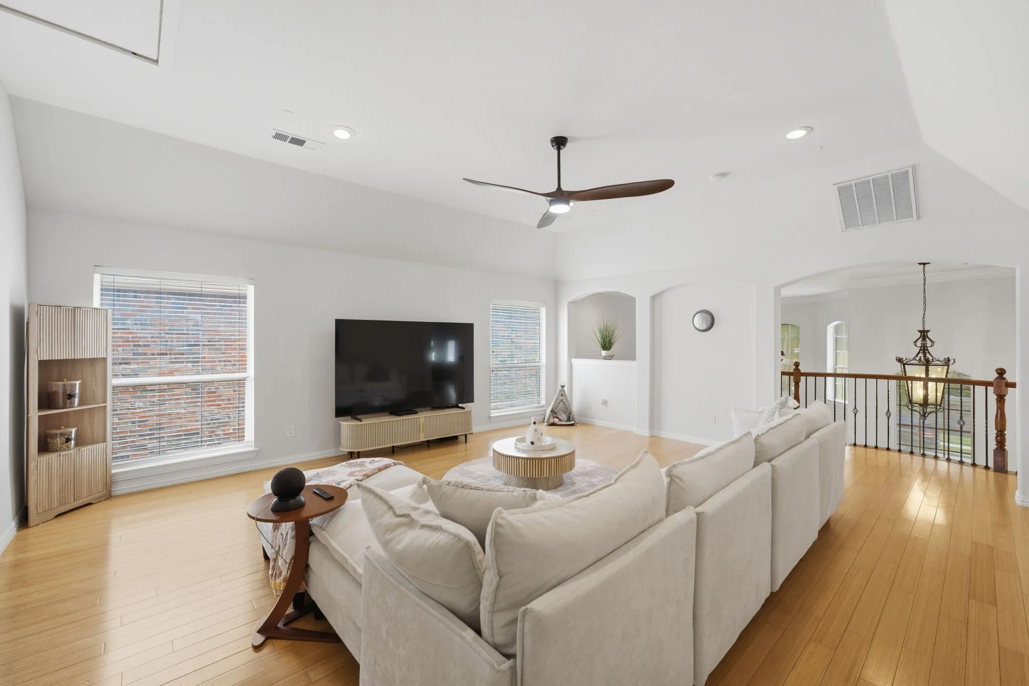 Vaulted ceiling, recessed lighting, wood-finish flooring, ceiling fan, and open railing