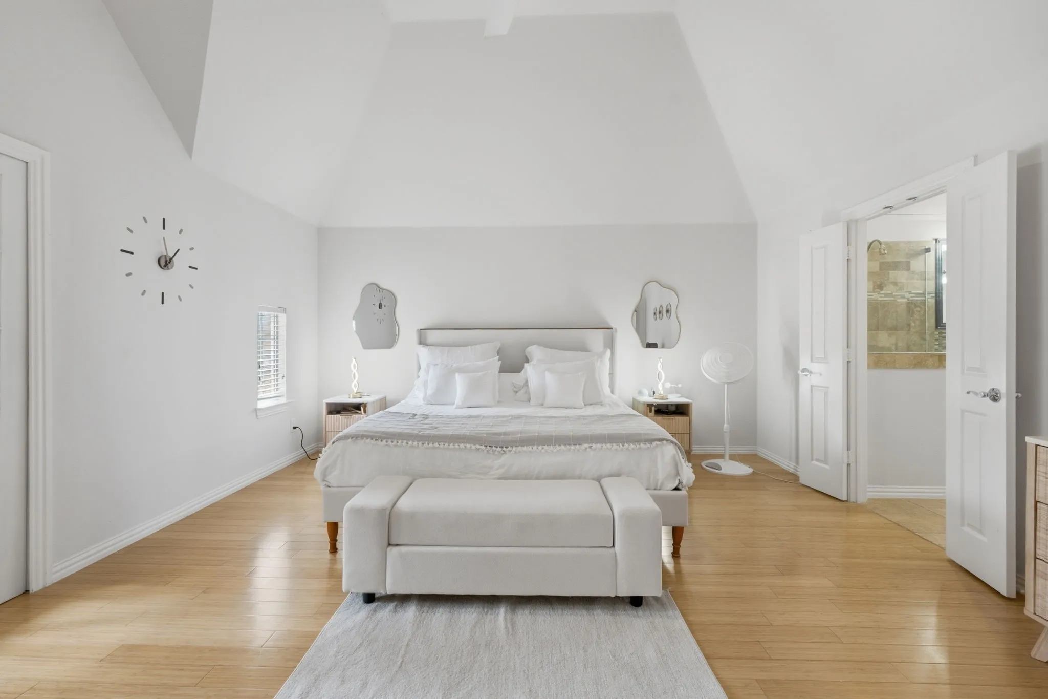 Vaulted ceiling, light wood-finish flooring, white walls, and double doors to an adjoining space