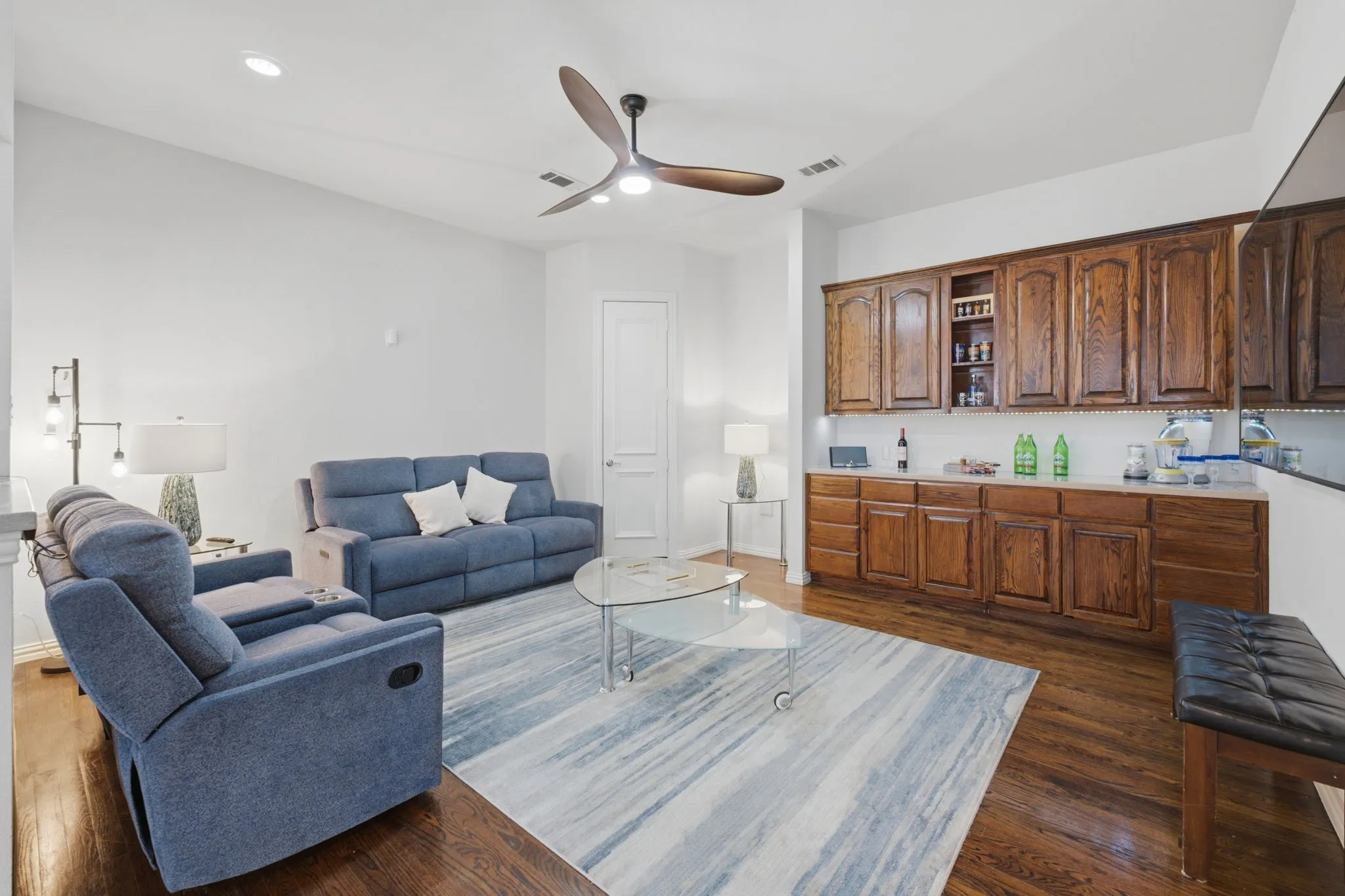 Vaulted ceiling with a contemporary ceiling fan, wood-finish flooring, built-in cabinetry, and recessed lighting