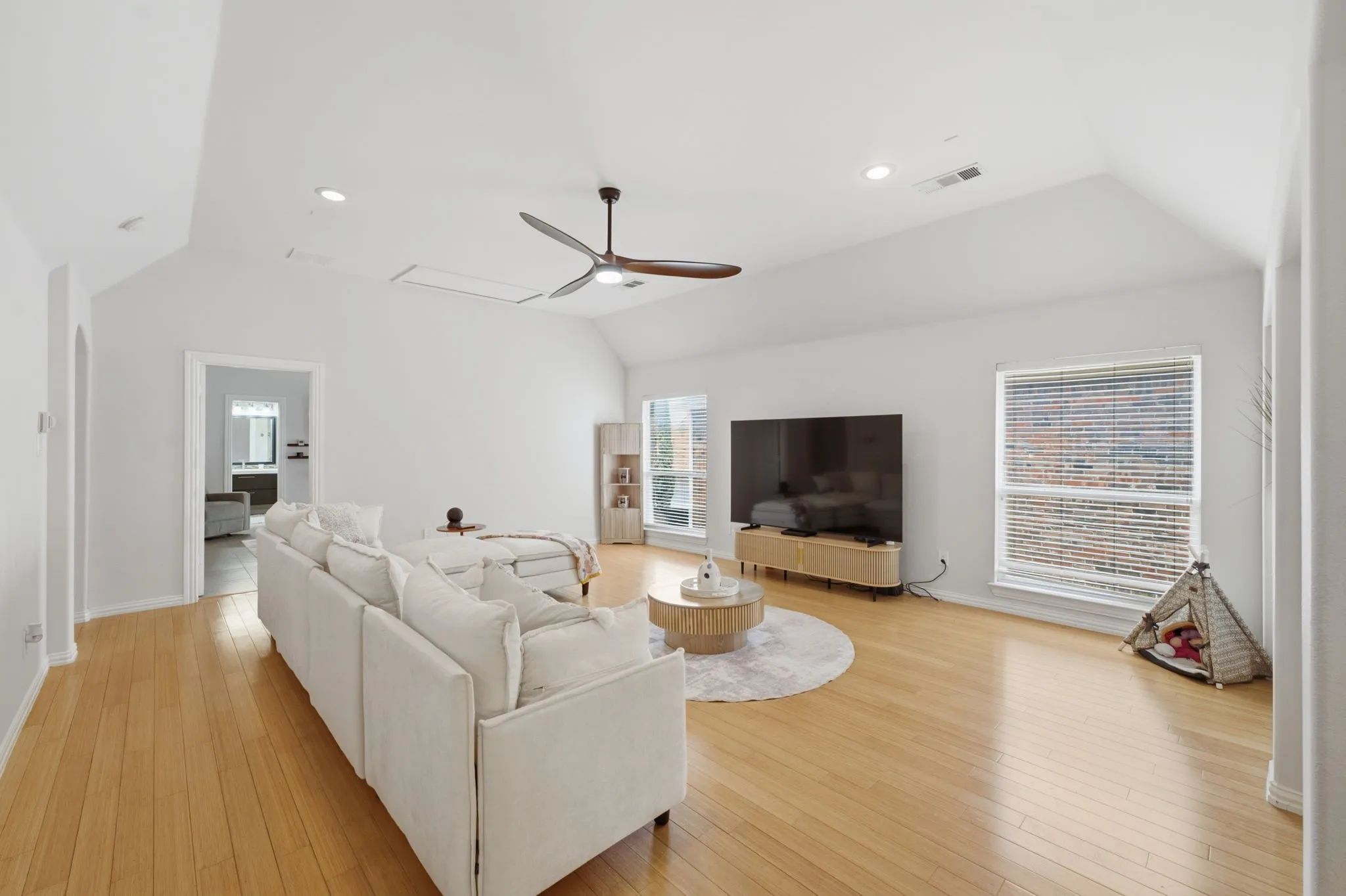 Vaulted ceiling with recessed lighting, wood-finish flooring, ceiling fan, and multiple windows with blinds