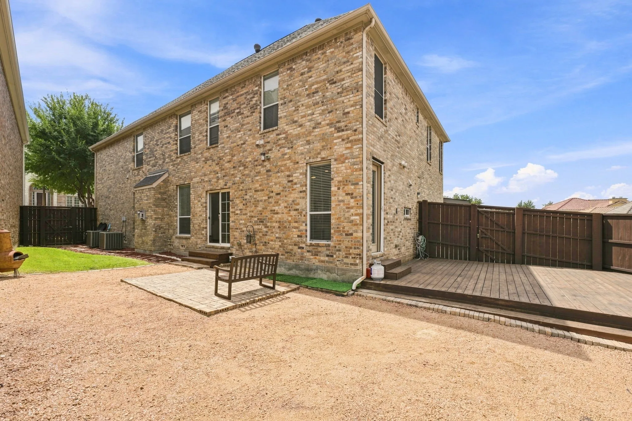 Brick exterior, elevated wood deck, private wood fencing, sliding glass door, paver patio