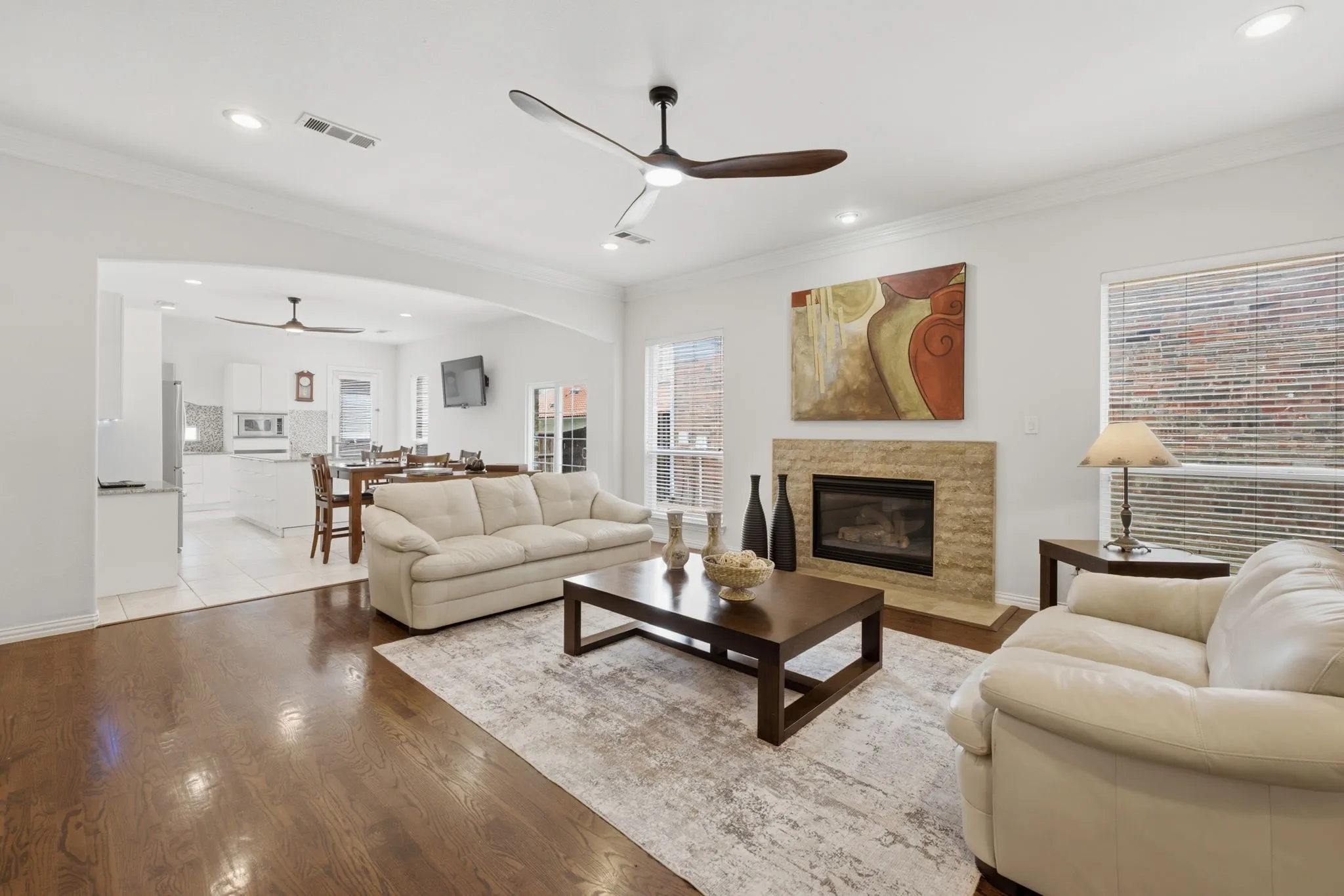 Spacious living area featuring wood-finish flooring, recessed lighting, and a stone-clad fireplace