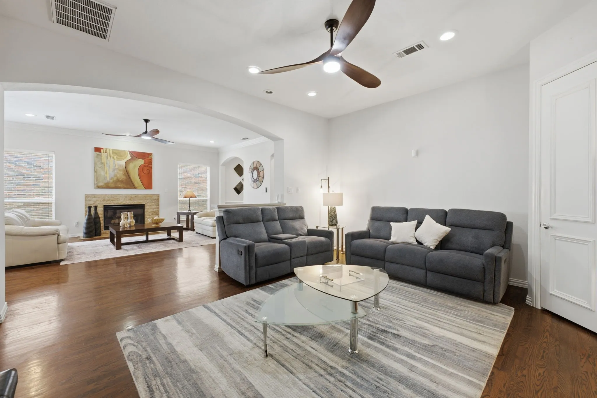 Hardwood flooring throughout, recessed lighting, arched doorways, and a stone-clad fireplace