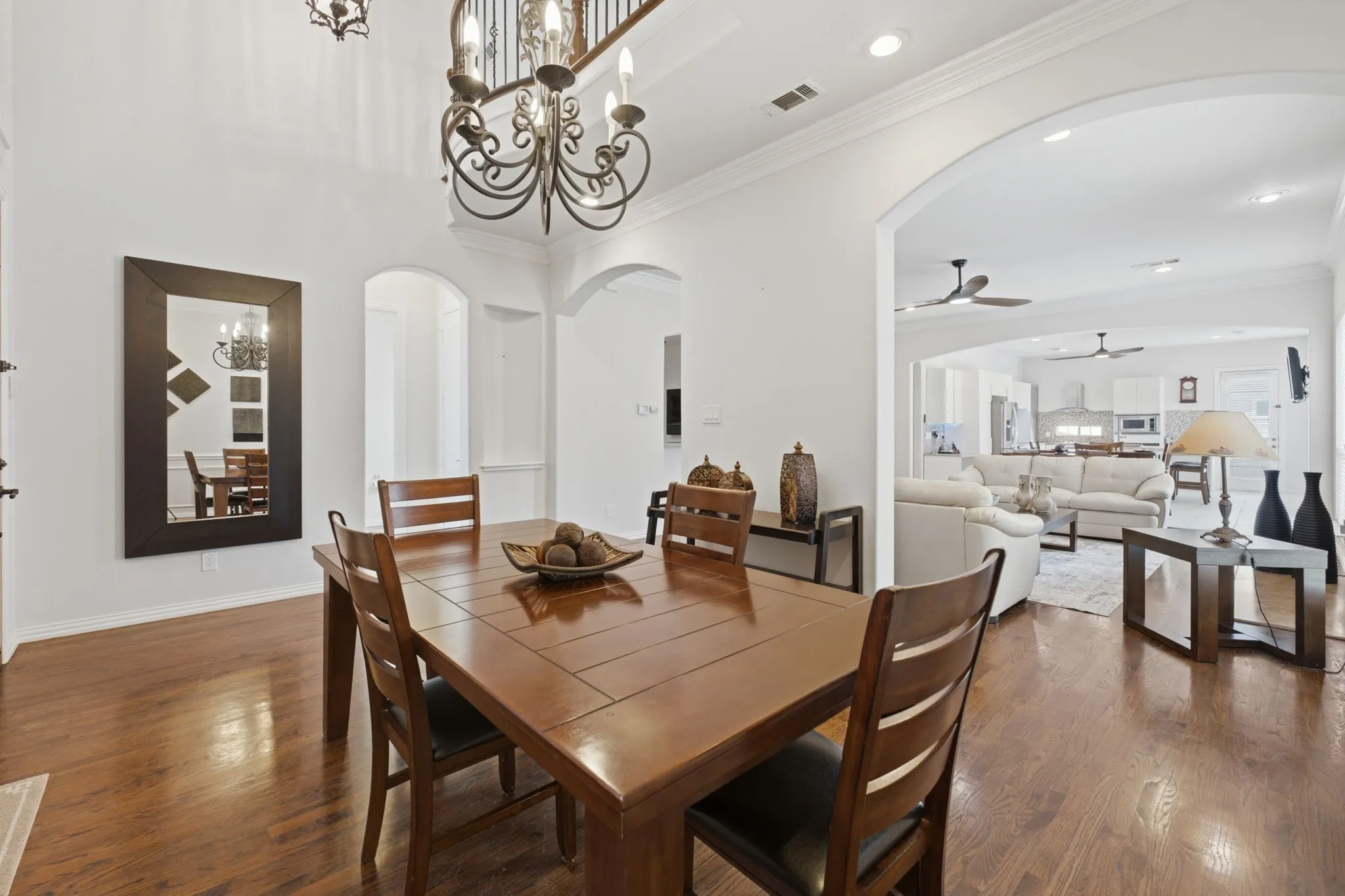 Wood-finish flooring throughout, ornate chandelier, arched doorways, and recessed lighting