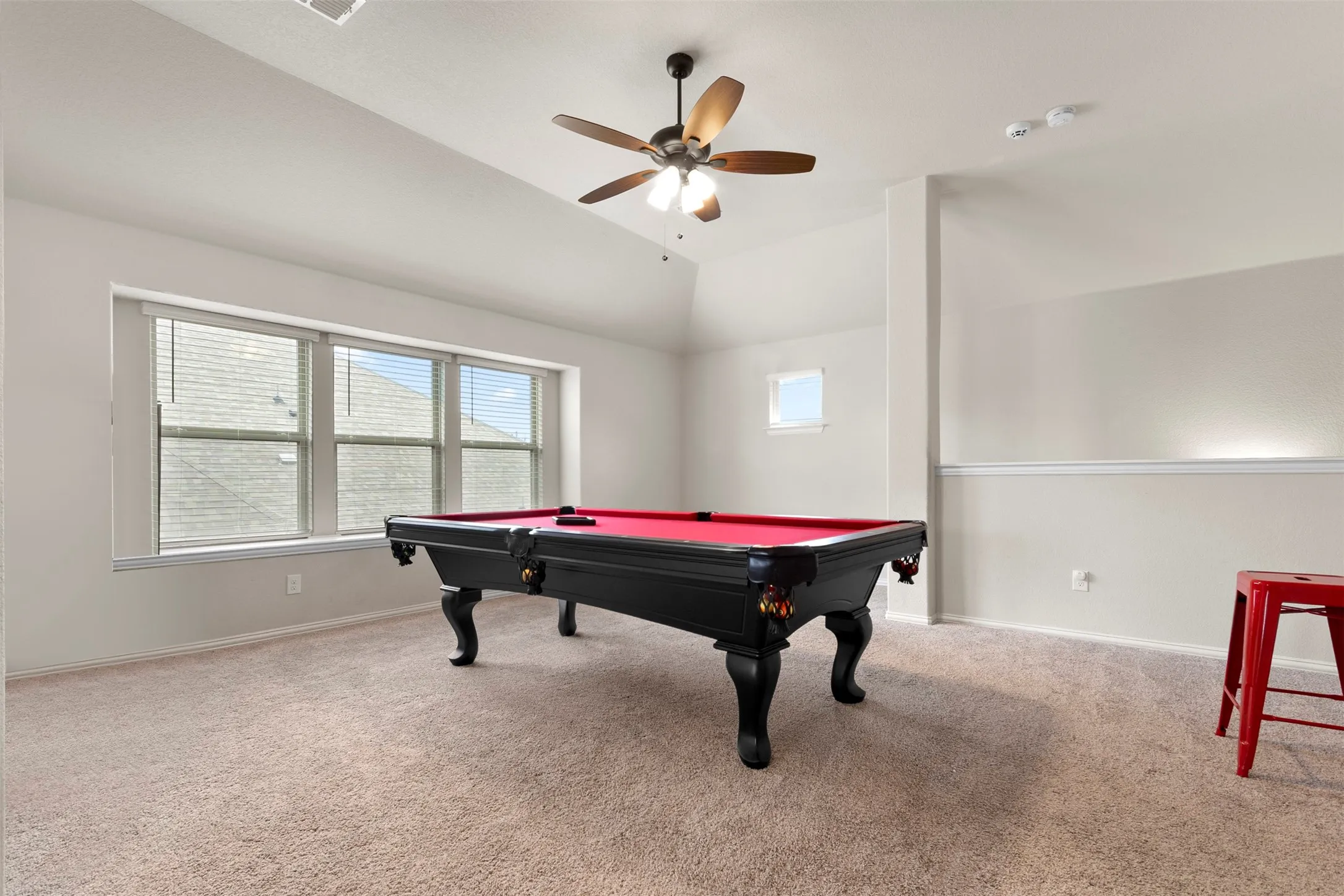 Spacious room with vaulted ceiling and a ceiling fan with light fixture