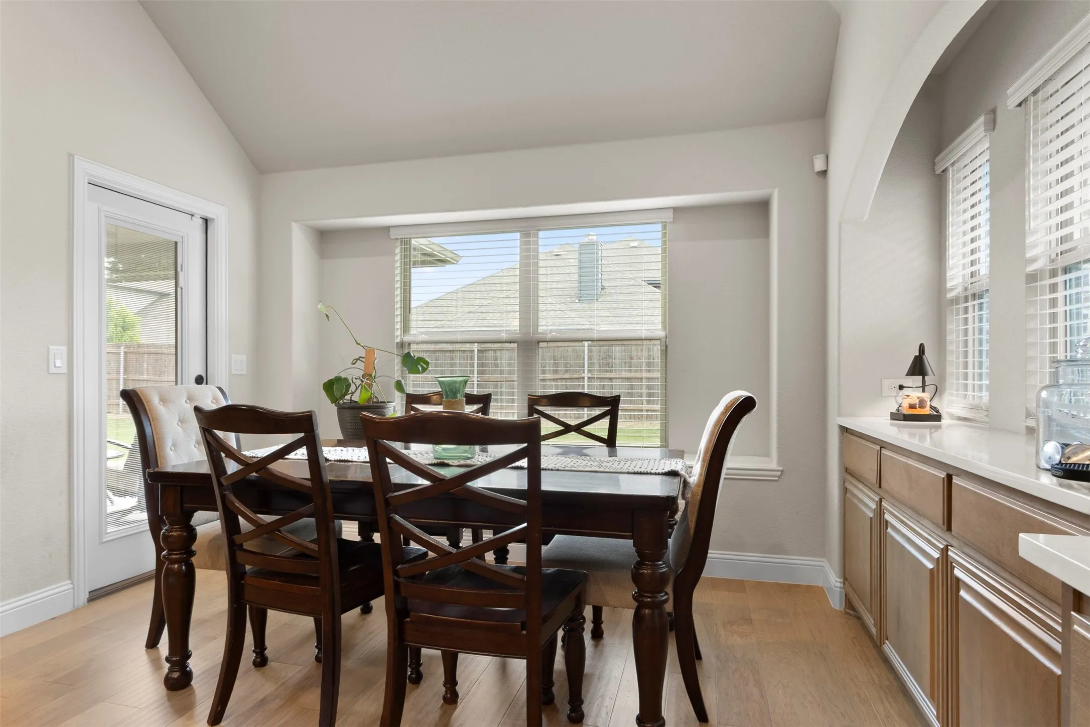 Vaulted ceiling, wood-finish flooring, built-in cabinetry, solid surface countertop, and large glass paneled door