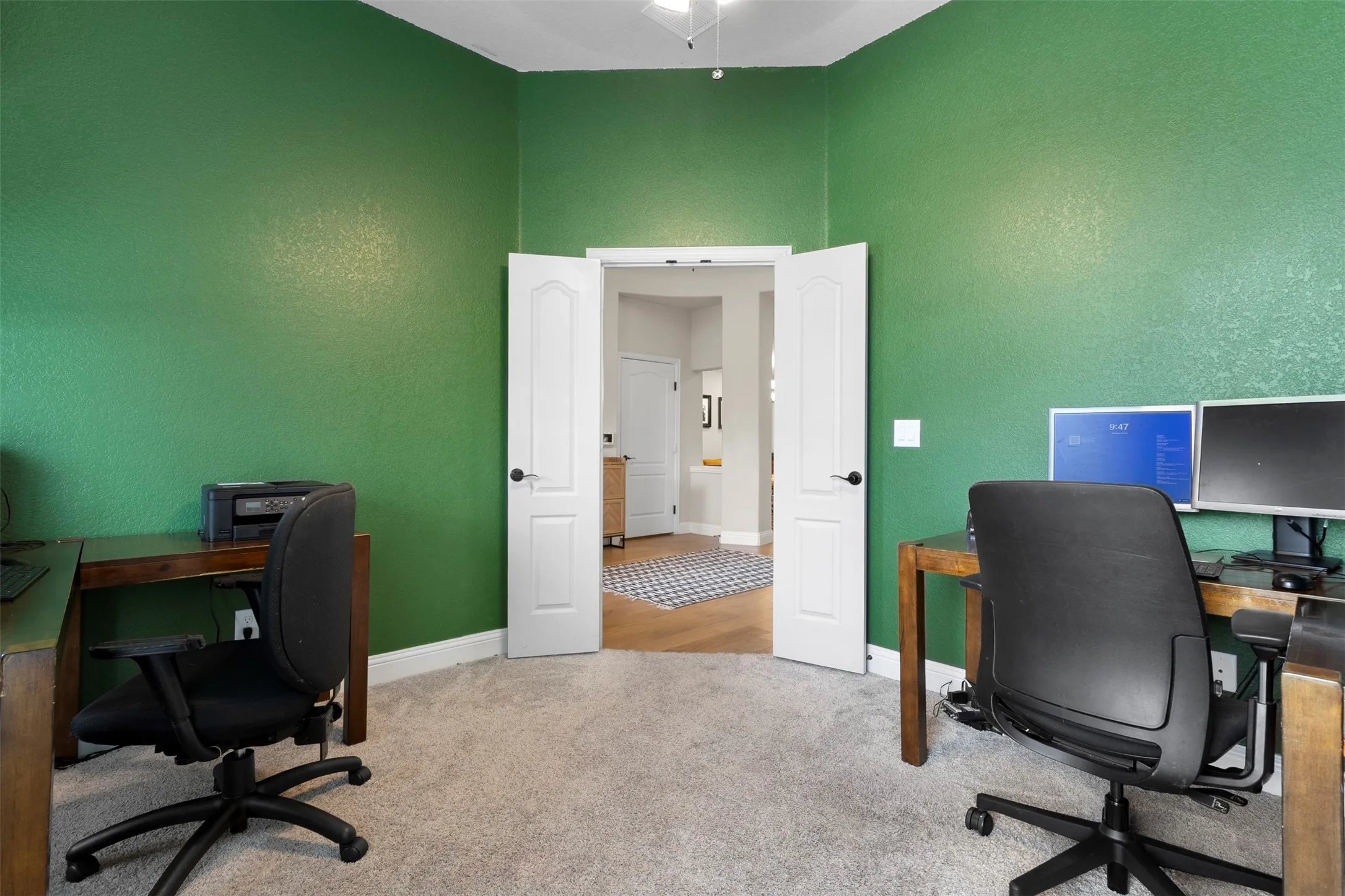 Double French doors, textured green walls, vaulted ceiling, and carpeted flooring