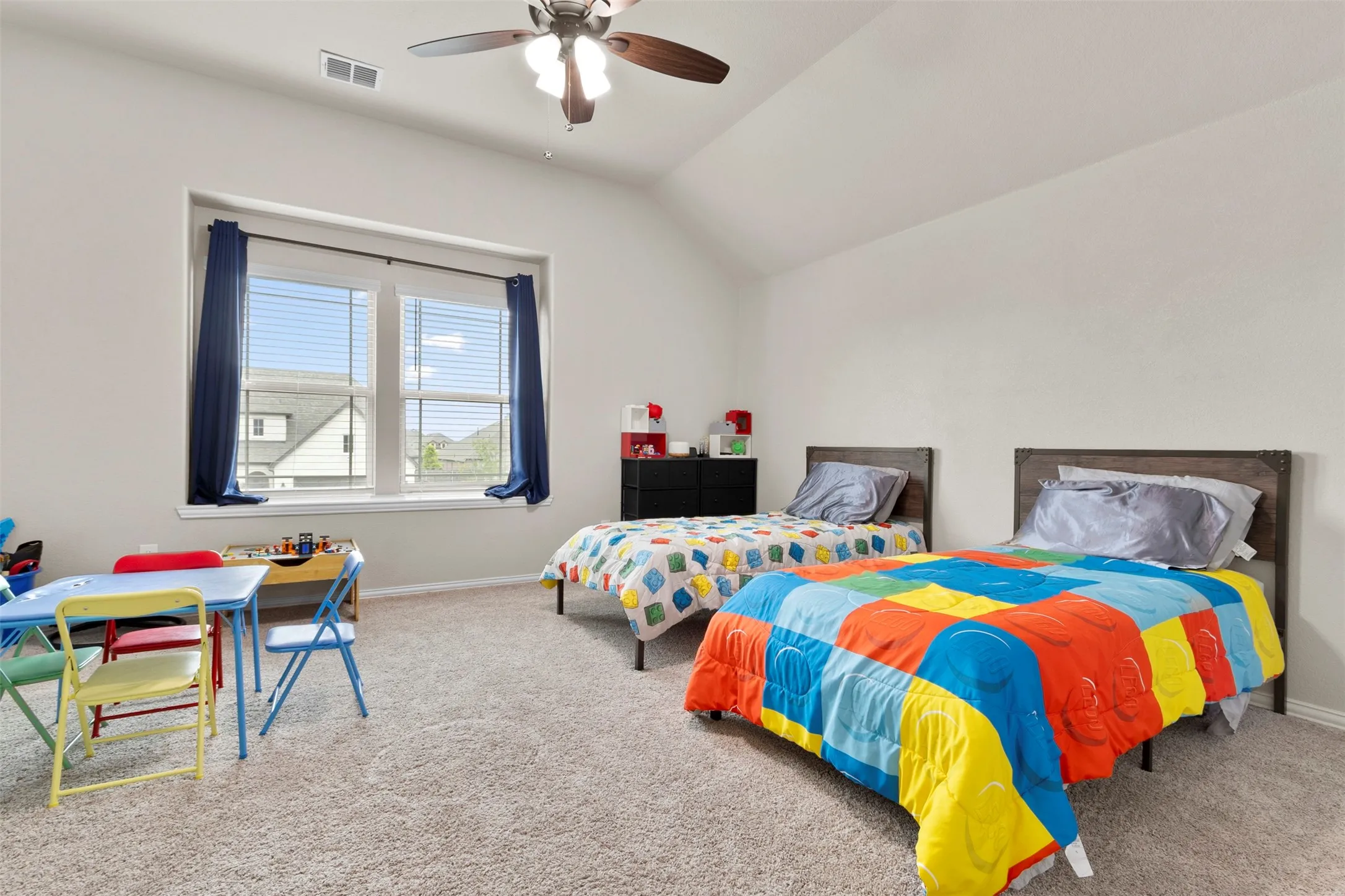 Vaulted ceilings, carpeted flooring, window with blinds, and a ceiling fan