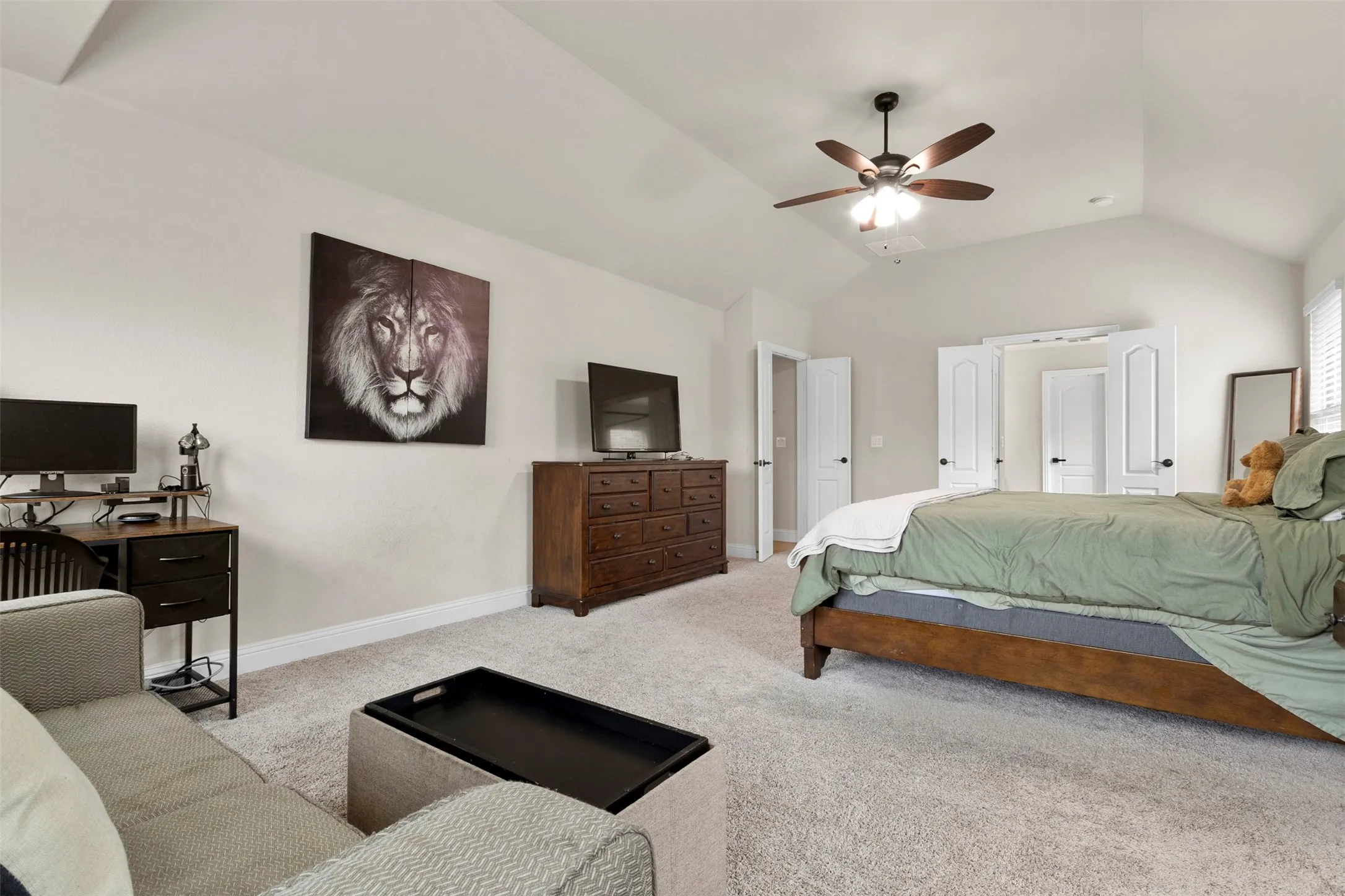 Vaulted ceiling with a ceiling fan, light gray carpeting, and white interior doors
