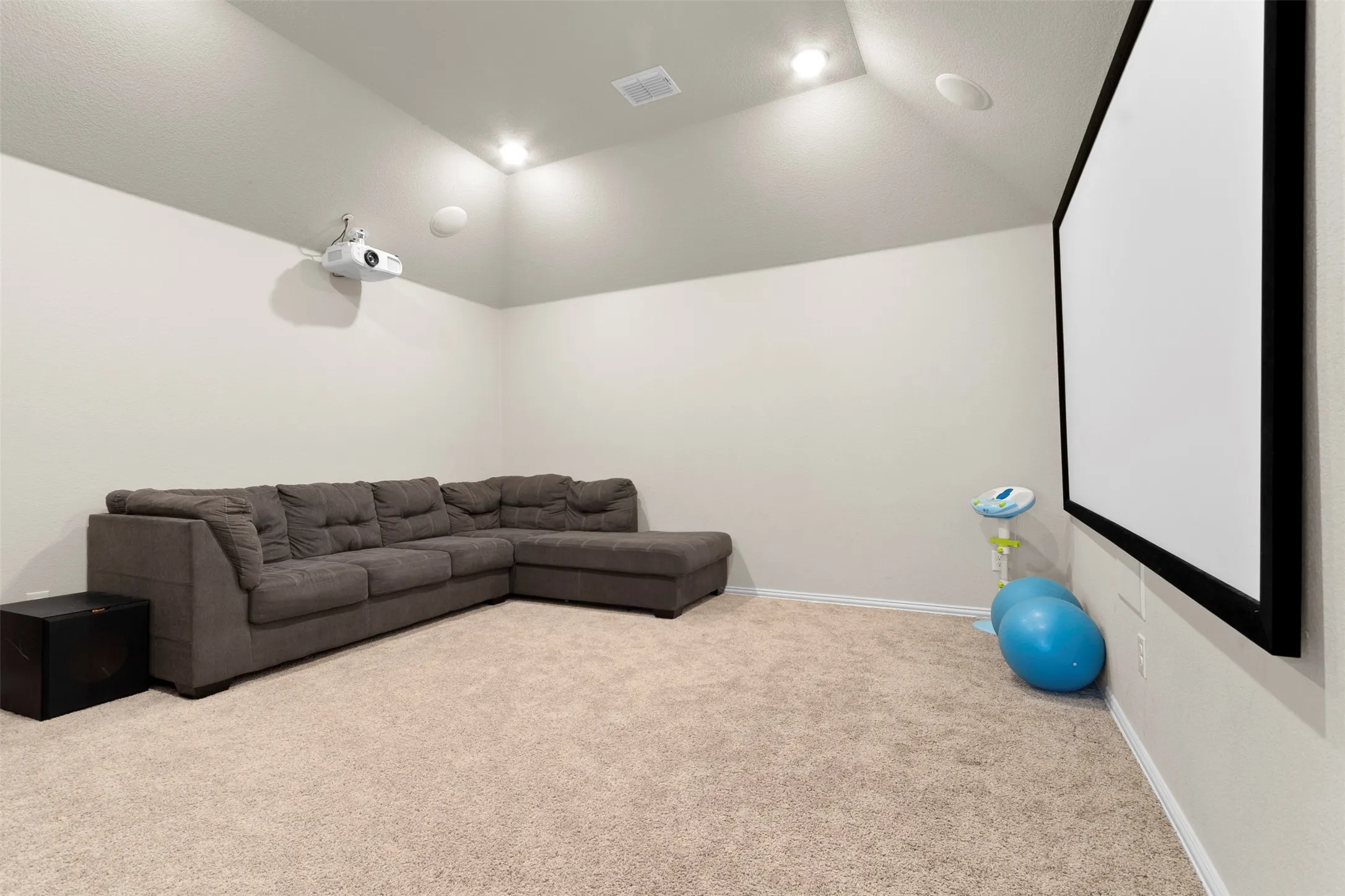 Vaulted ceiling, recessed lighting, built-in projector, large projection screen, and neutral carpet flooring