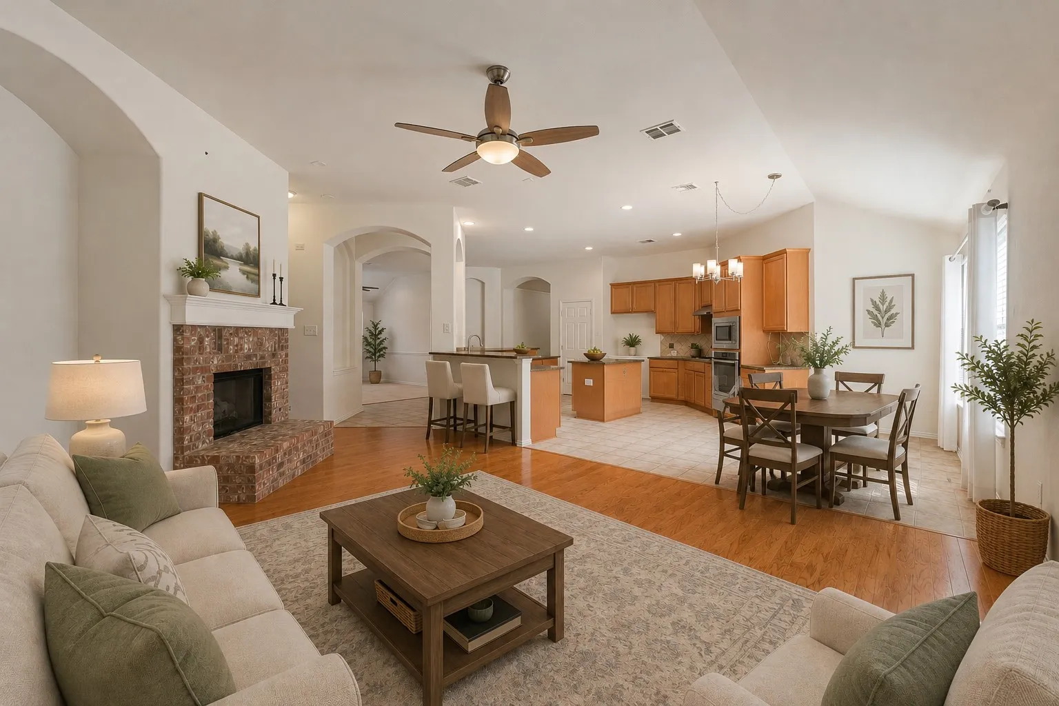 Brick-clad fireplace with mantel, wood-finish flooring, vaulted ceilings, kitchen with wood cabinetry, and a dining area with pendant lighting