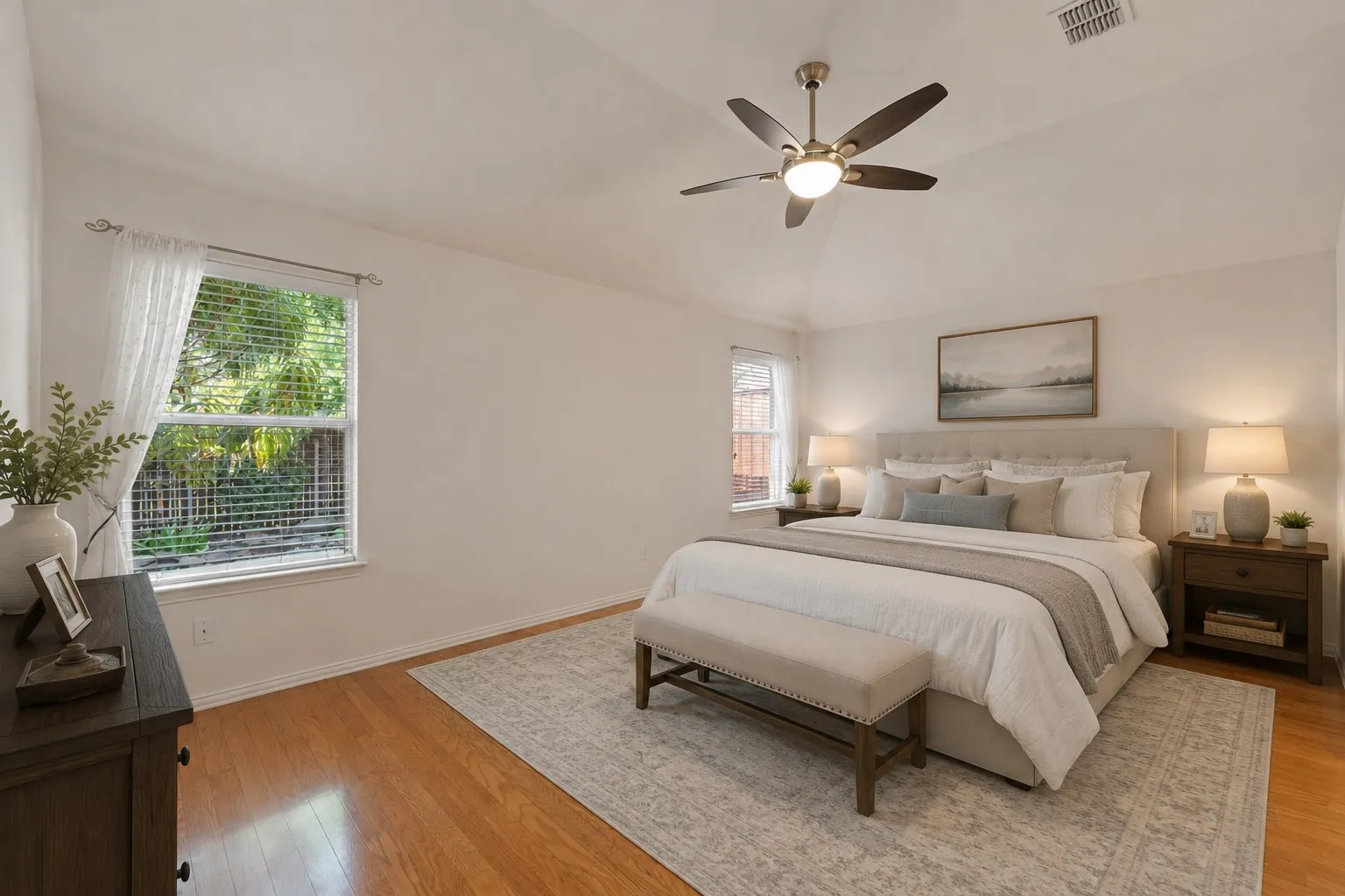 Vaulted ceiling with a ceiling fan, wood-finish flooring, and multiple windows
