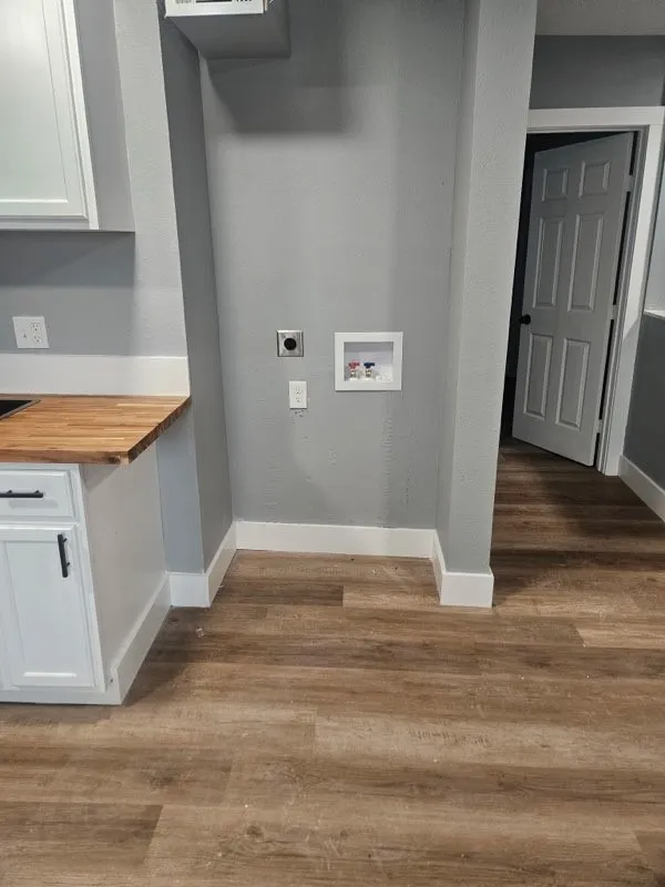 Dedicated laundry area with hookups, wood-finish flooring, white cabinetry, and a butcher block countertop