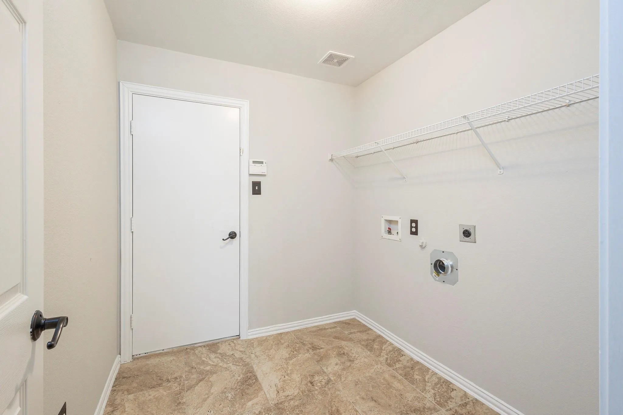 Utility room with tile flooring, wall-mounted wire shelving, and appliance hookups