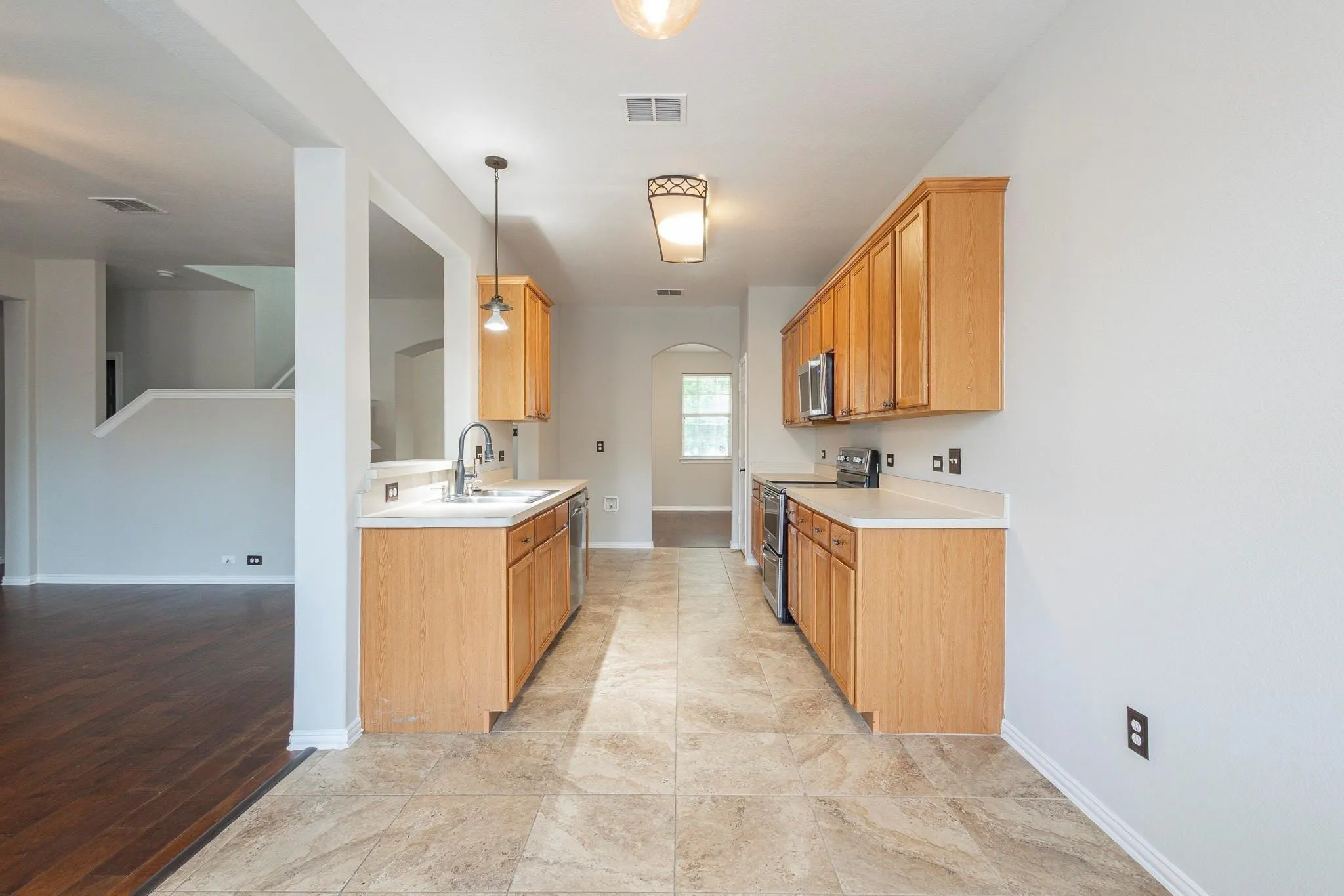 Kitchen featuring wood cabinetry, stone-finish tile flooring, recessed lighting, and stainless steel appliances