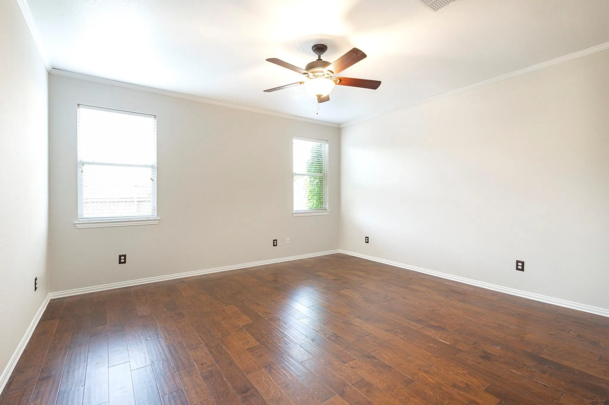Wood-finish flooring, dual windows, ceiling fan with integrated lighting, and crown molding