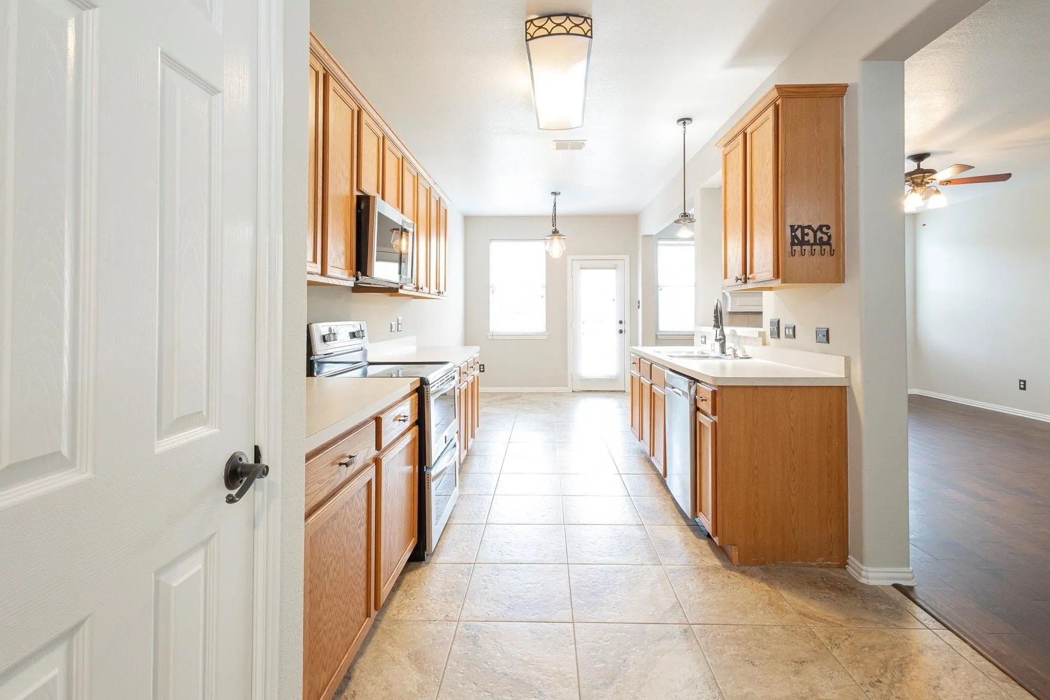 Kitchen featuring light wood-finish cabinetry, stainless steel appliances, white countertops, and tile flooring