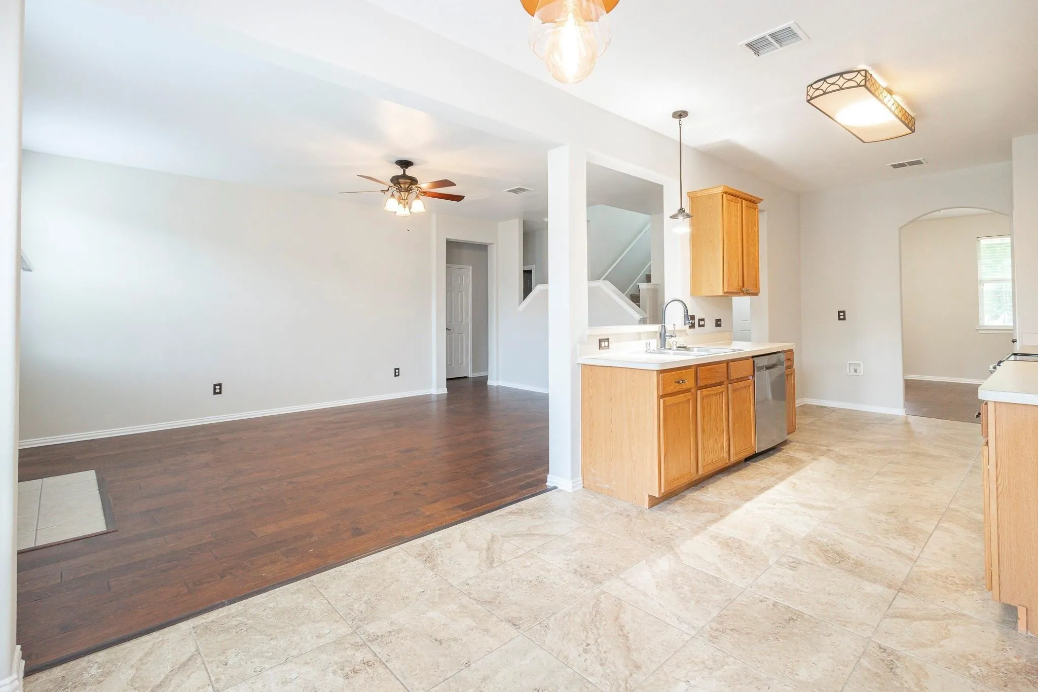 Tile flooring, wood-finish flooring, wood cabinetry, stainless steel dishwasher, and a ceiling fan