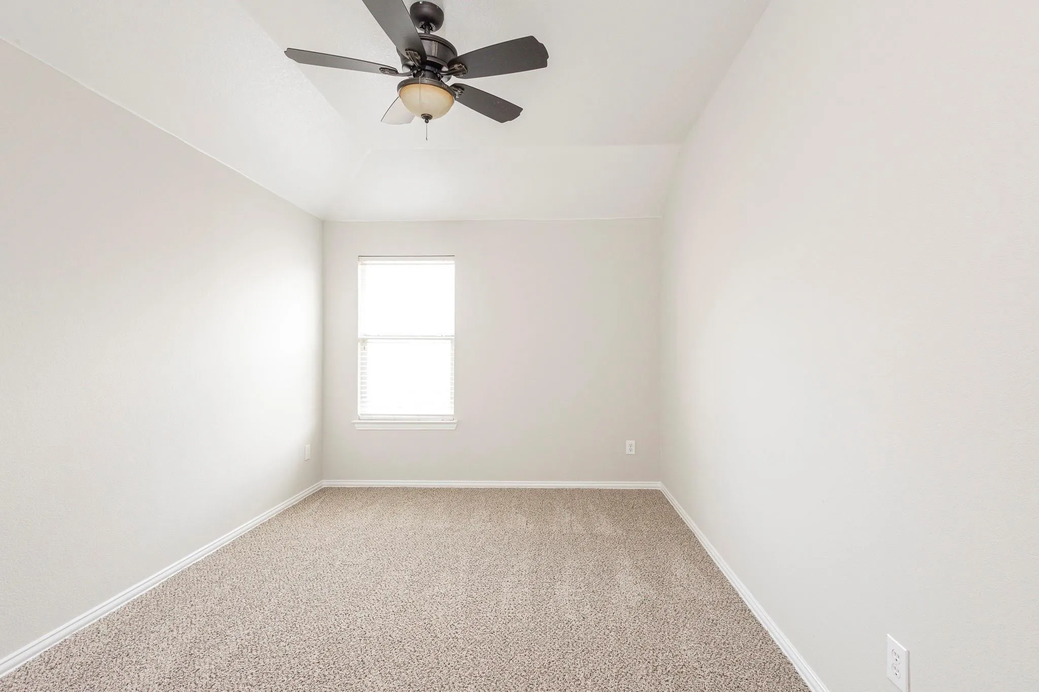 Vaulted ceiling with a ceiling fan light fixture, neutral carpeting, and a window with blinds
