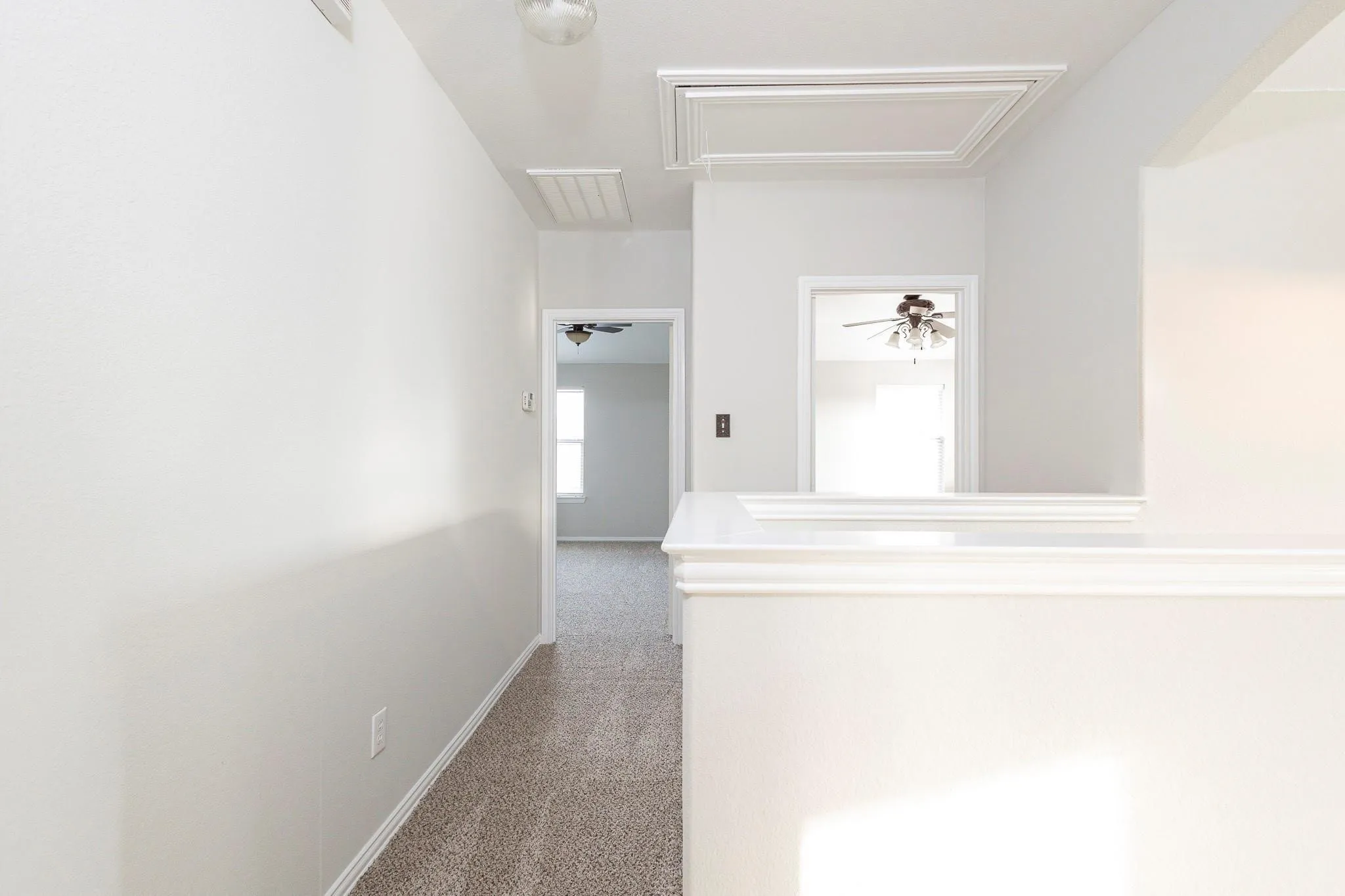 Hallway with neutral carpeting, painted walls, and ceiling-mounted lighting fixtures